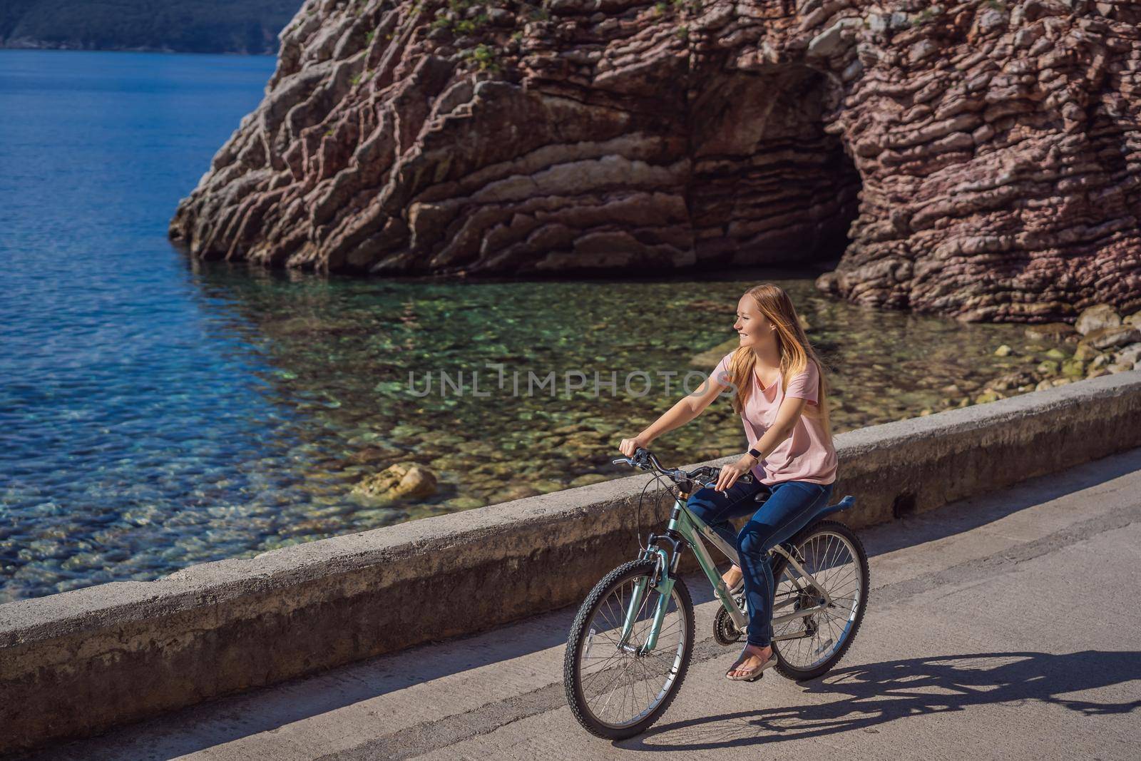 Woman tourist on a bicycle explores Budva in Montenegro. Cycling in Montenegro concept by galitskaya