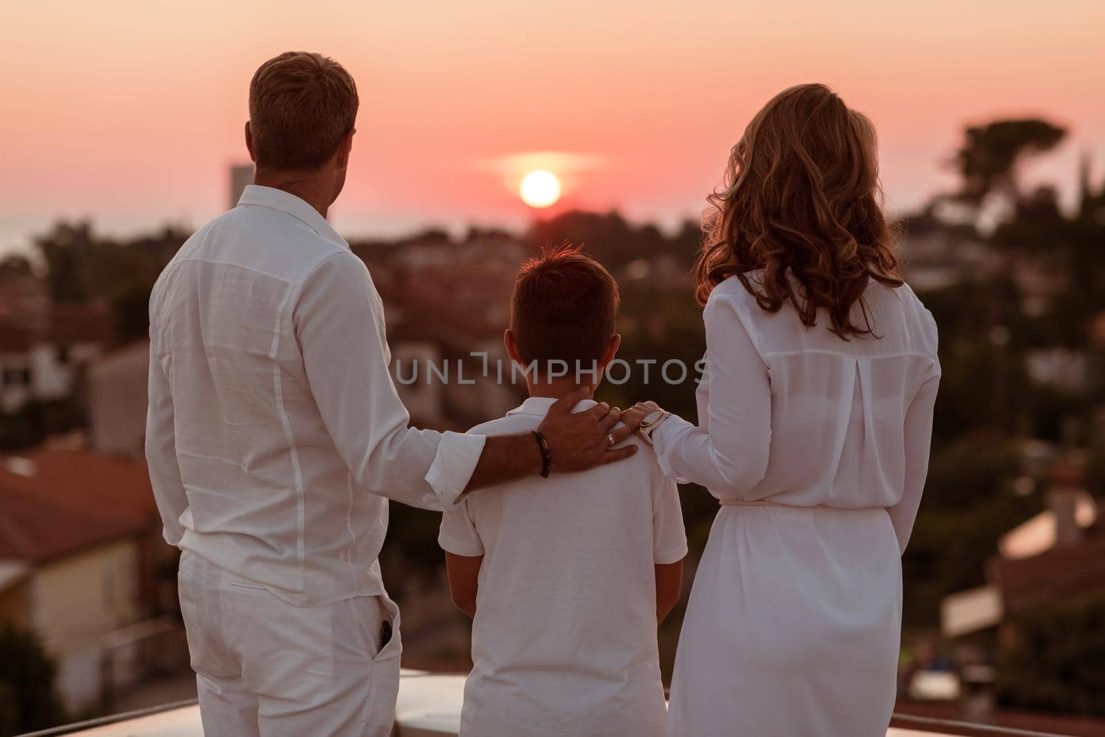Happy family enjoys and spends time together on the roof of the house while watching the sunset on the open sea together by dotshock