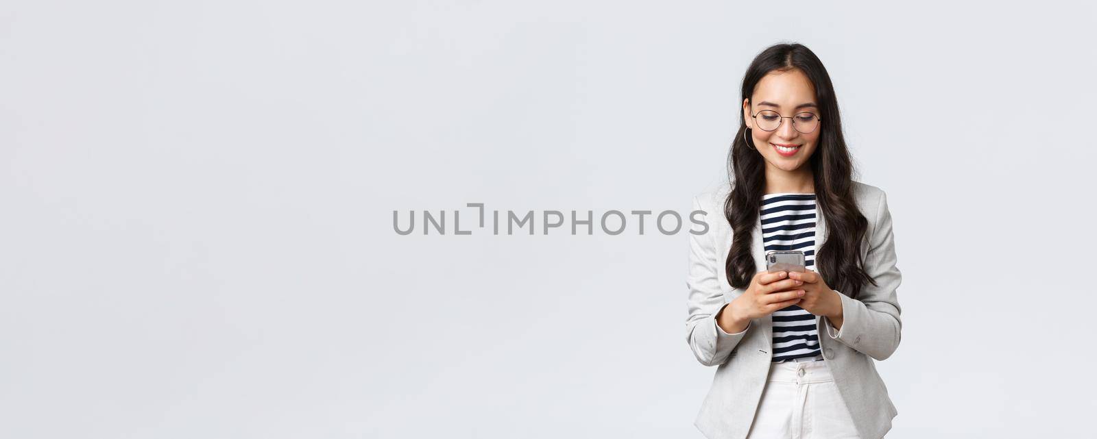 Business, finance and employment, female successful entrepreneurs concept. Businesswoman waiting for client, checking messages in smartphone, wearing glasses as looking at mobile screen.