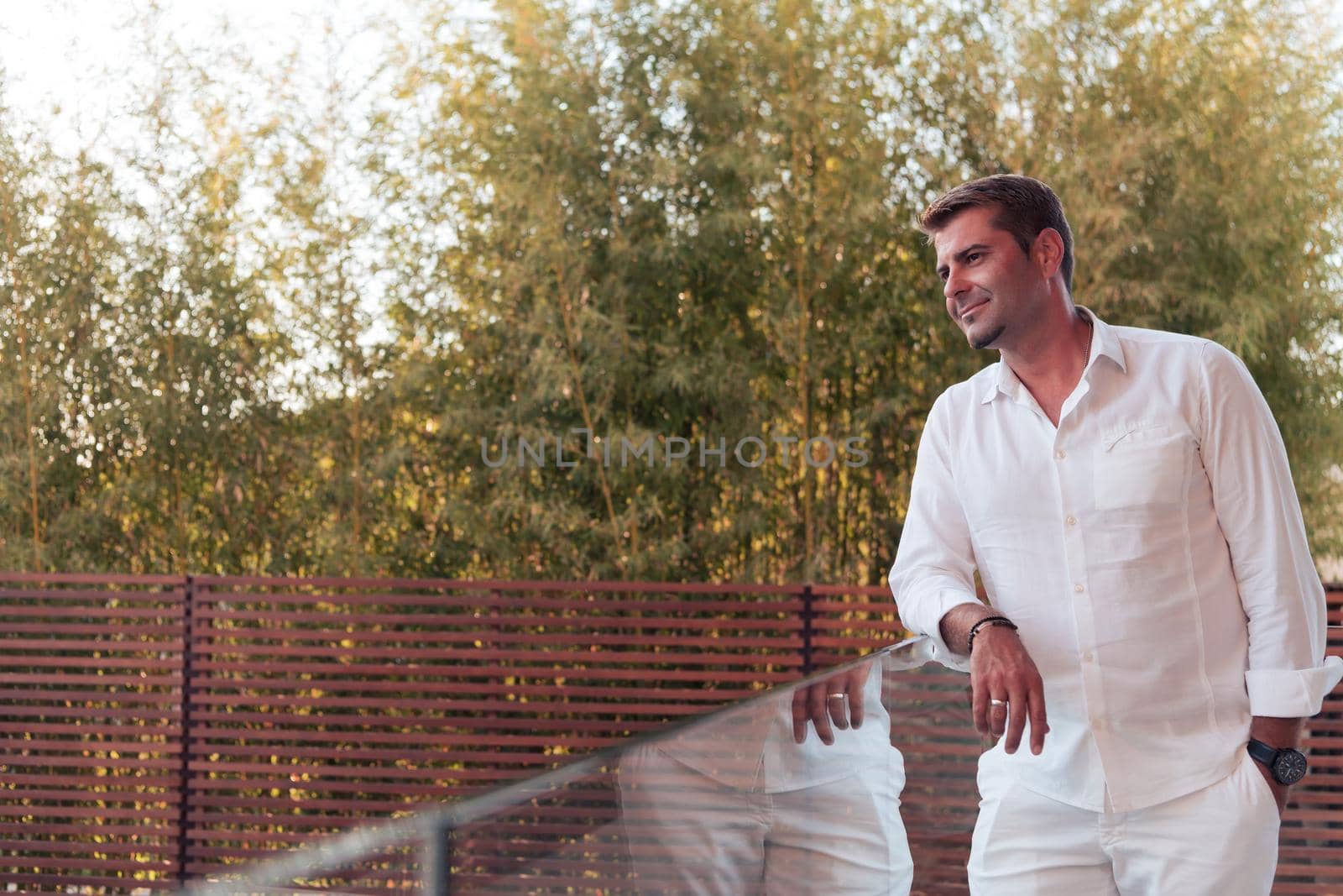 A businessman in casual clothes resting on the balcony of the terrace while using a smartphone. Selective focus. High-quality photo