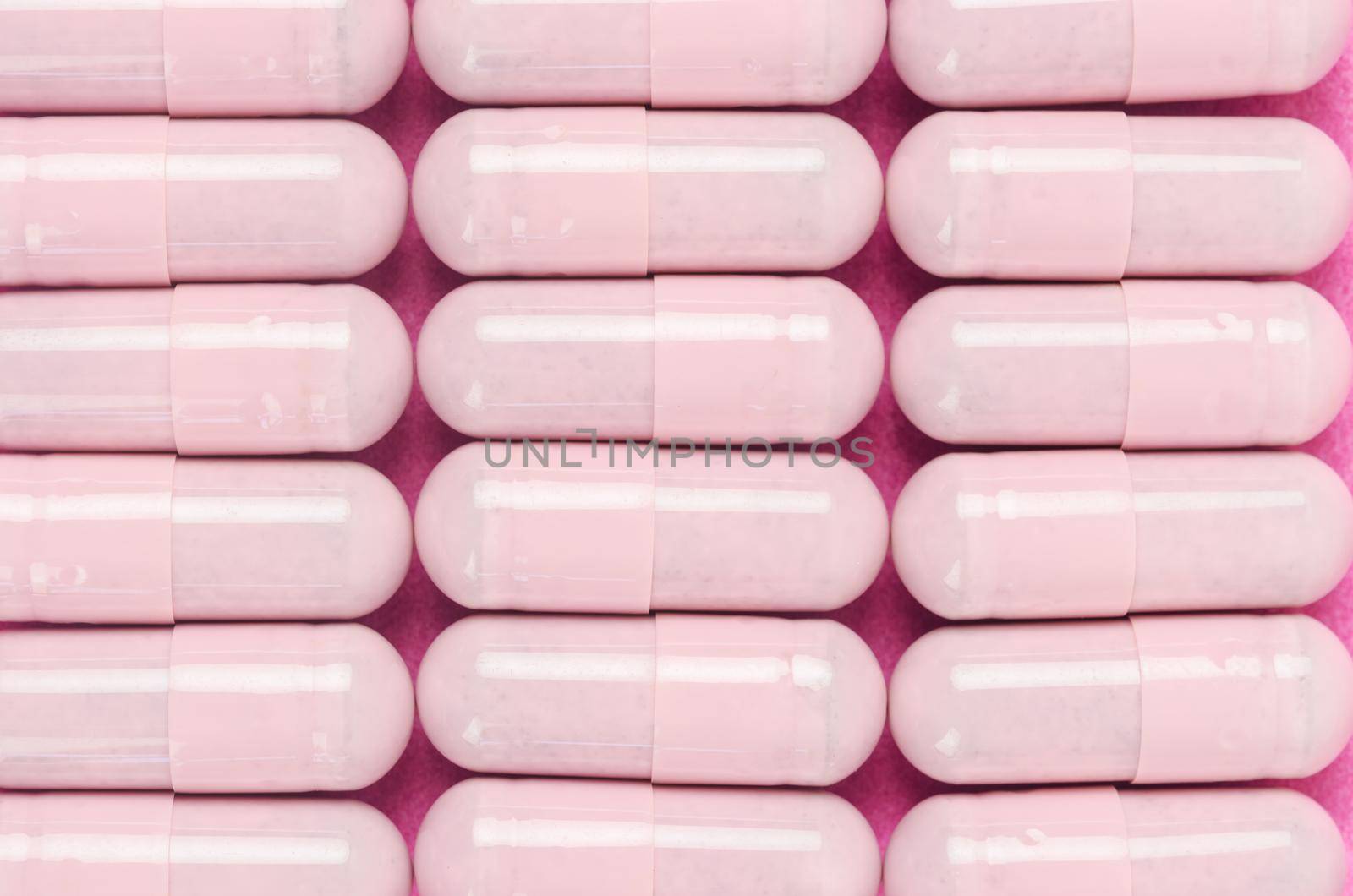 The Pink capsule pills on pink background.