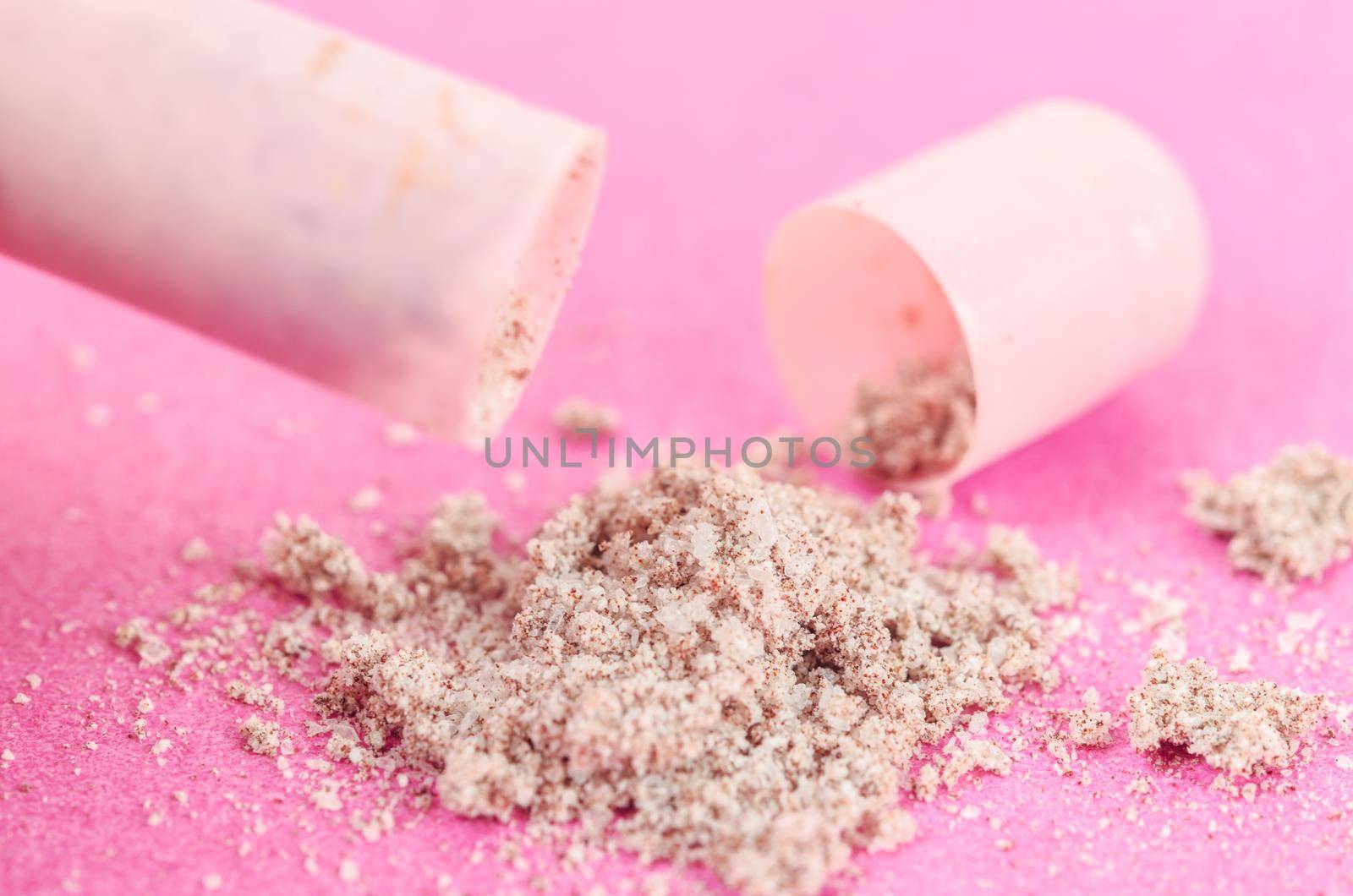 Open medical drug pill with white powder macro closeup on pink paper background