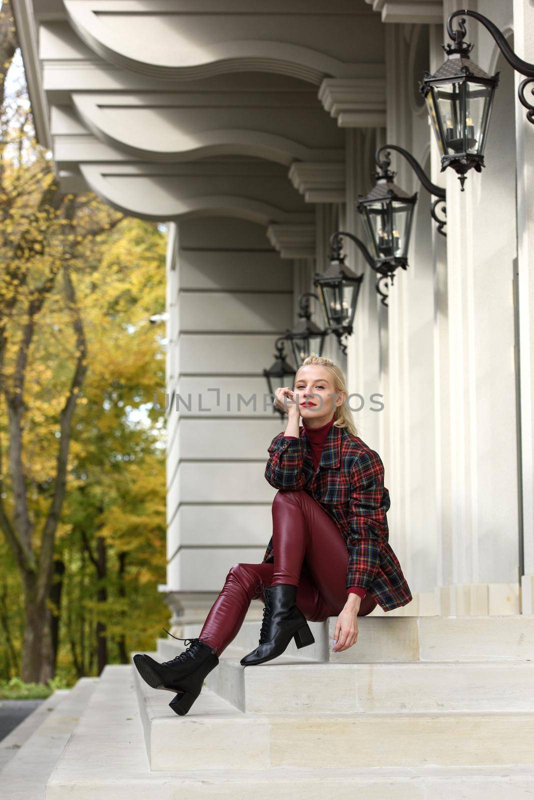 A beautiful, modern, fashionable blonde girl with a red lipstick posing outdoors . red leather leggings, turtleneck and checkered jacket. fit figure. by Ashtray25
