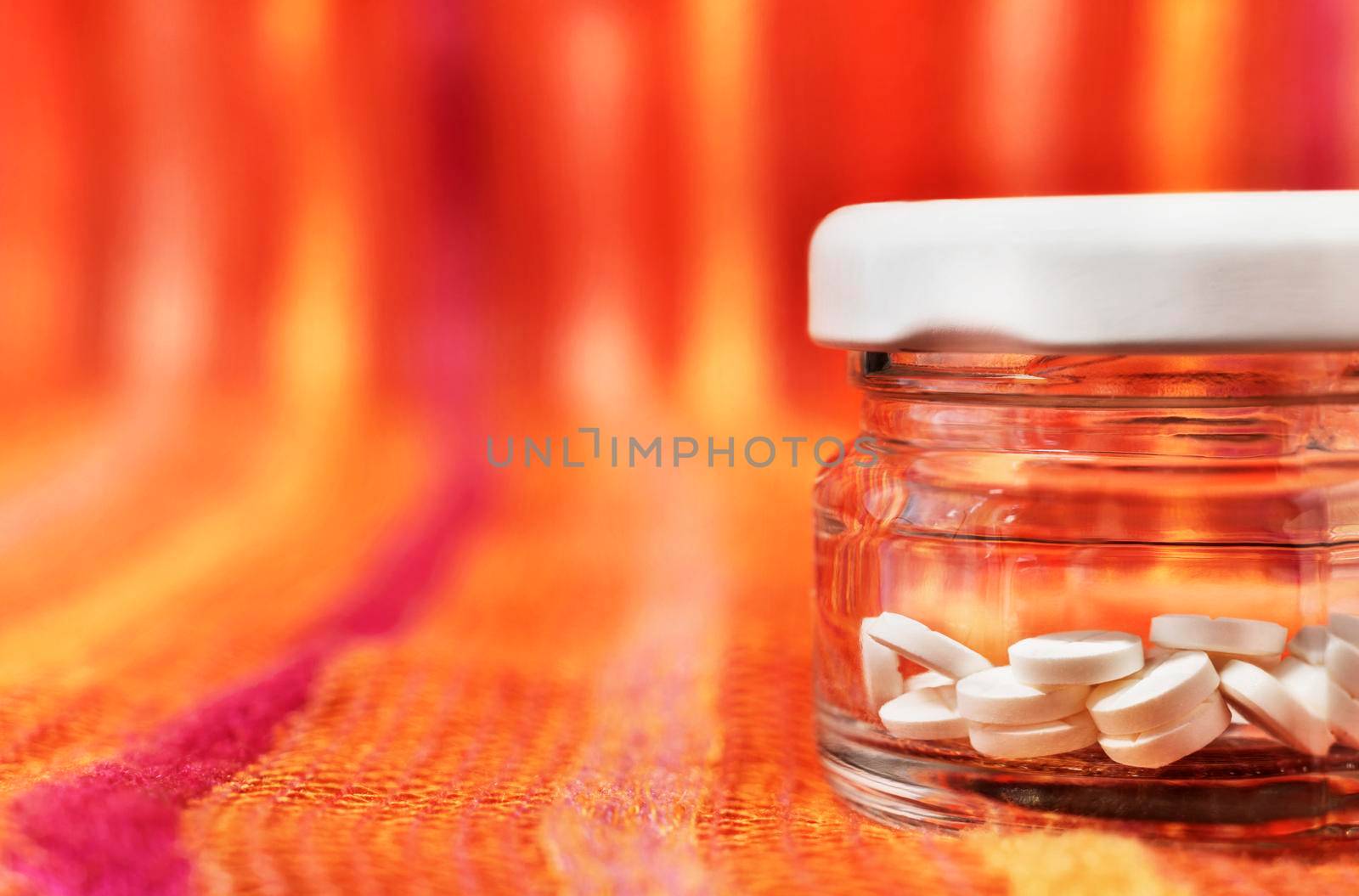 White pills in closed glass jar on colored background , hearth care  and medicine