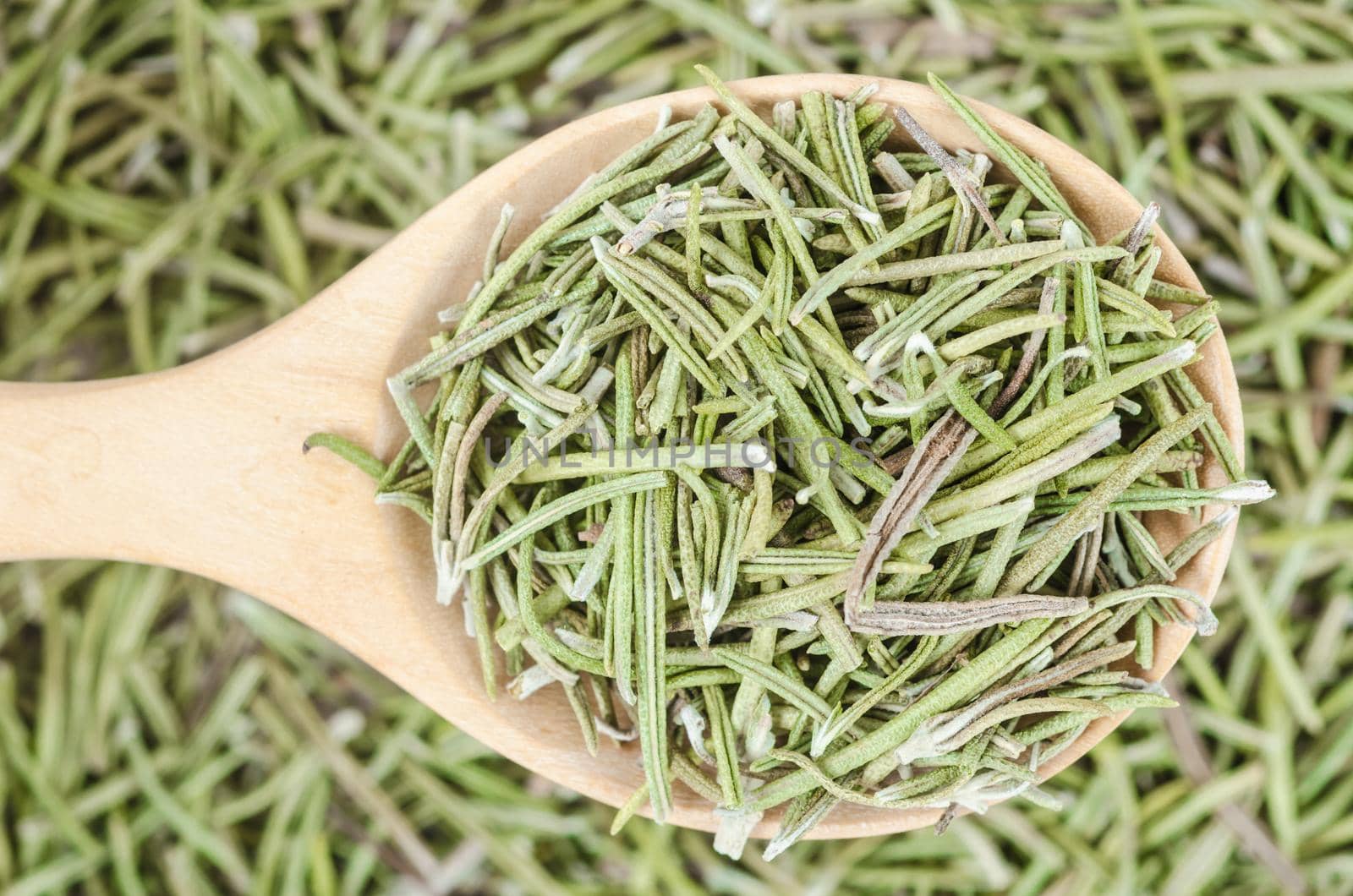 Dried rosemary spice in wooden spoon. Macro with shallow depth of field.