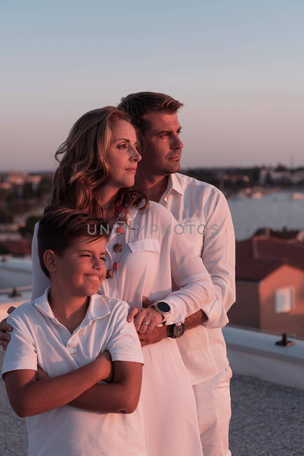 The happy family enjoys and spends time together on the roof of the house while watching the sunset on the open sea together. High-quality photo