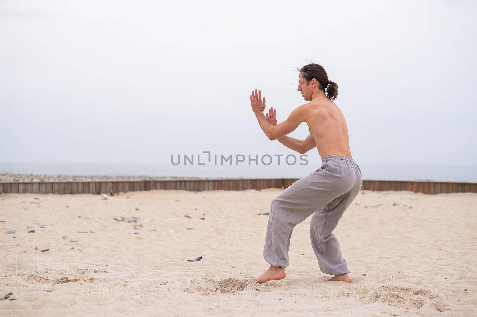 Caucasian man with long hair practicing qigong outdoors