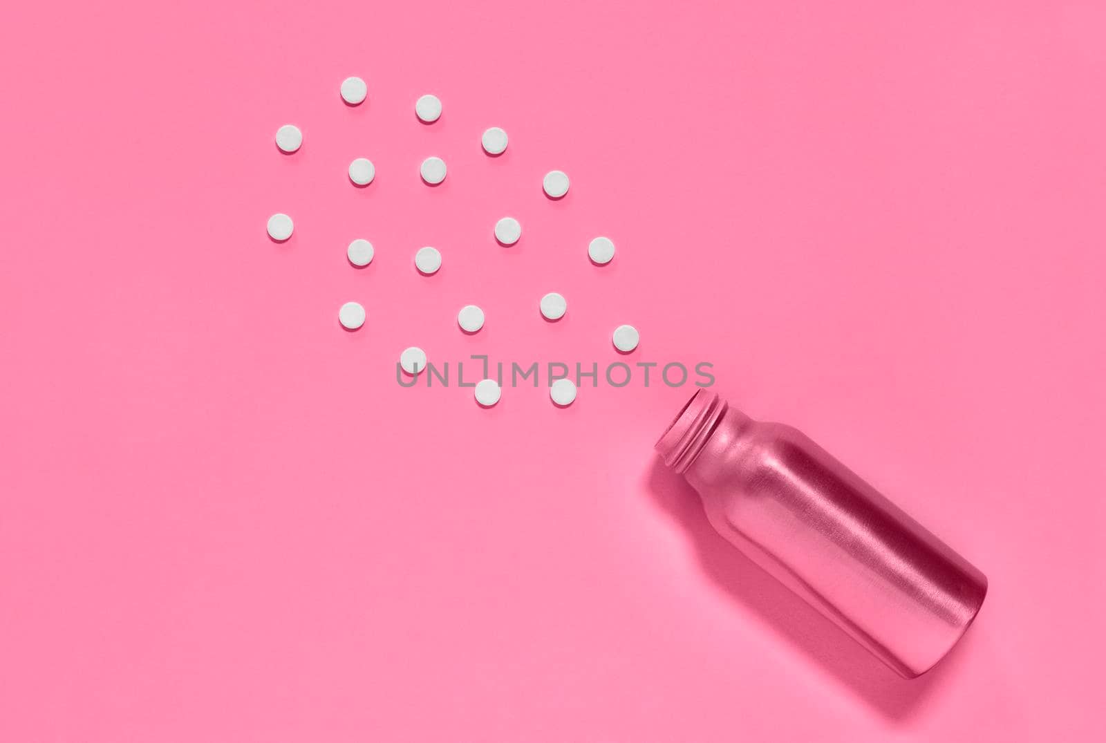 White pills and pink medicine bottle  on pink background , hearth care  and medicine