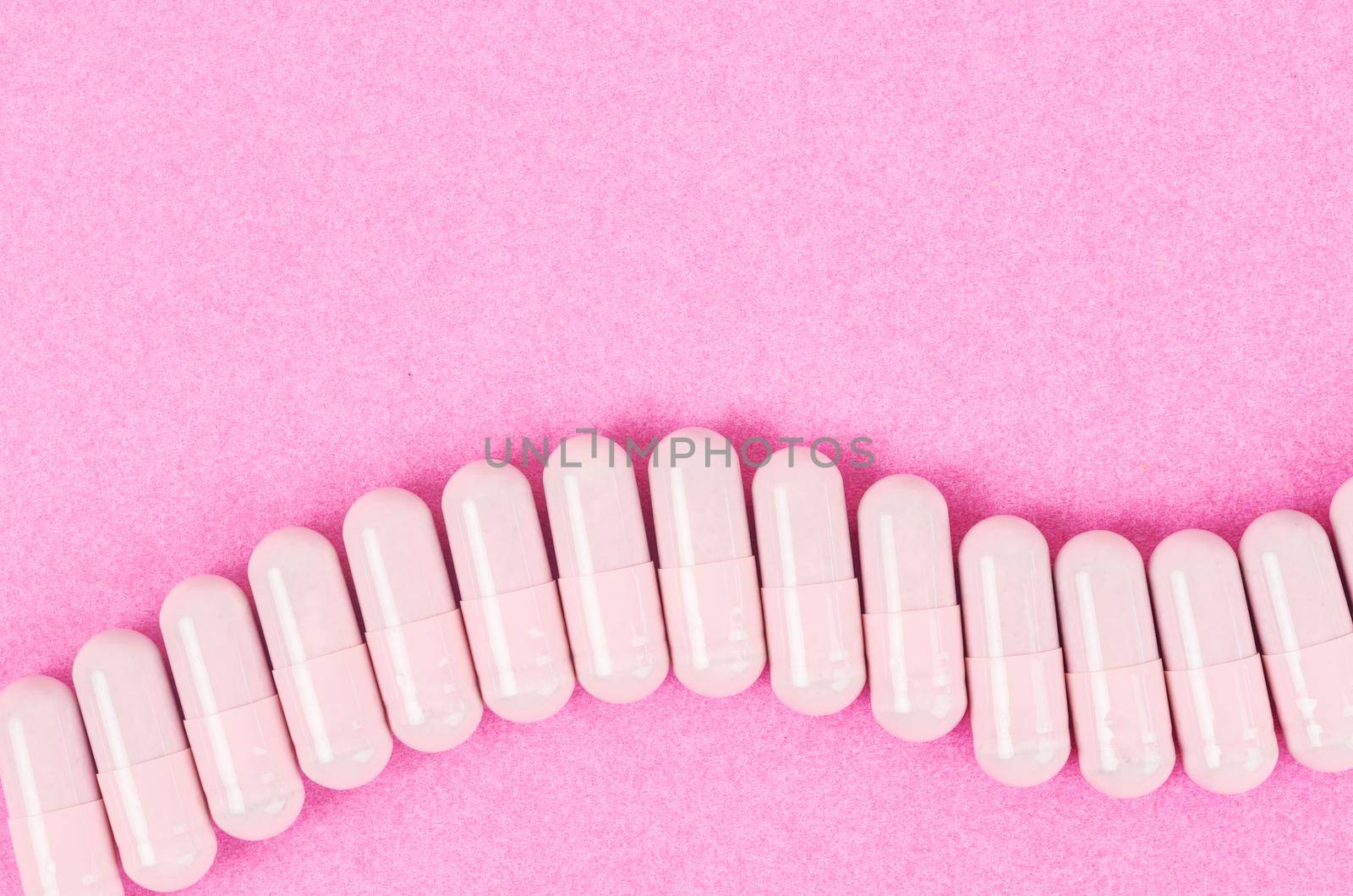 The Pink capsule pills on pink background with copy space.