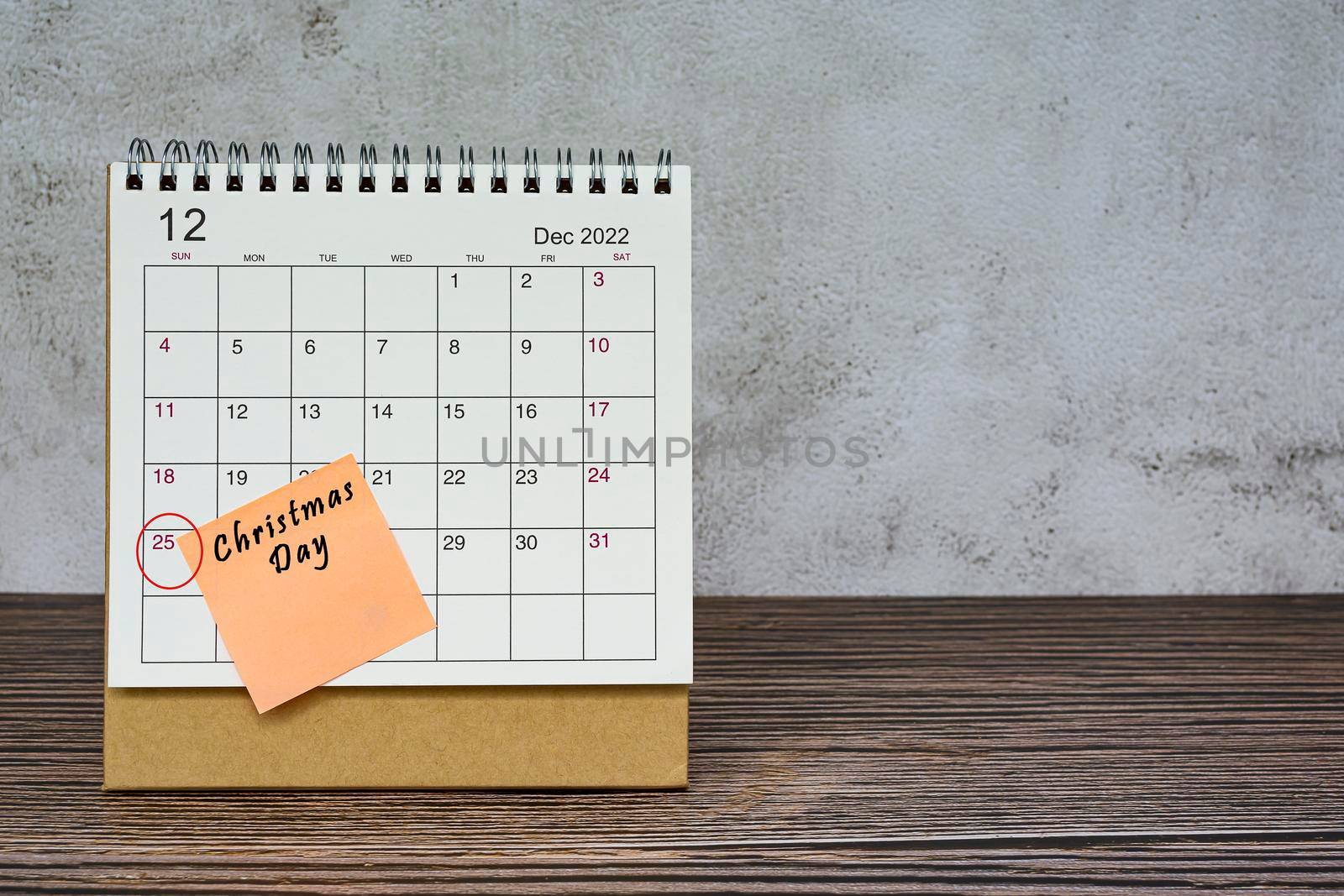 December 2022 calendar on wooden desk with date circle and text on sticky note. Christmas Day on 25th December 2022