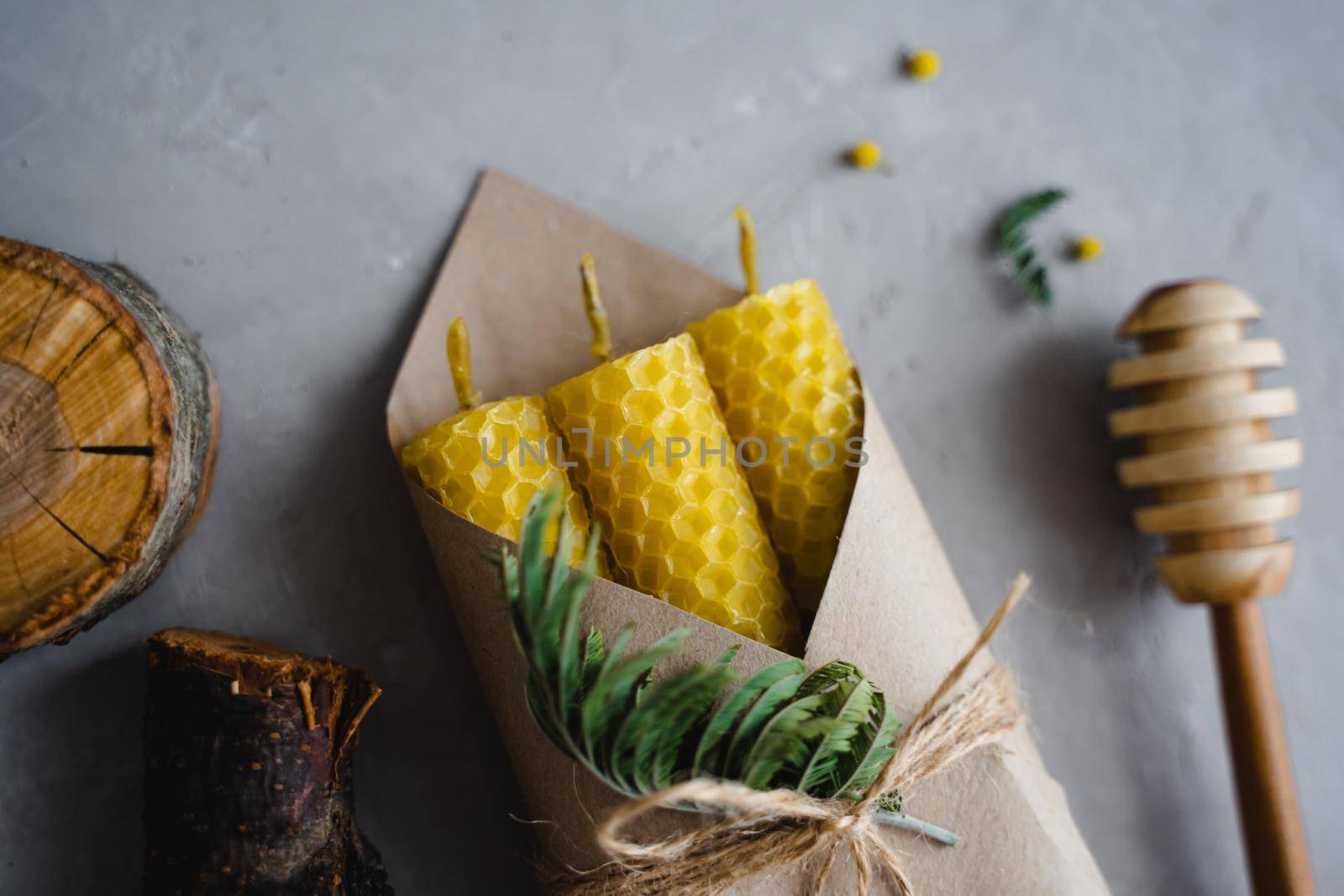 Set of honey candles in a craft envelope. A green twig. Wooden stick for honey. A natural product.