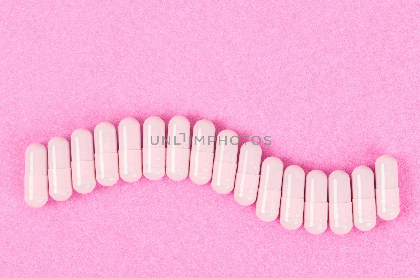The Pink capsule pills on pink background with copy space.