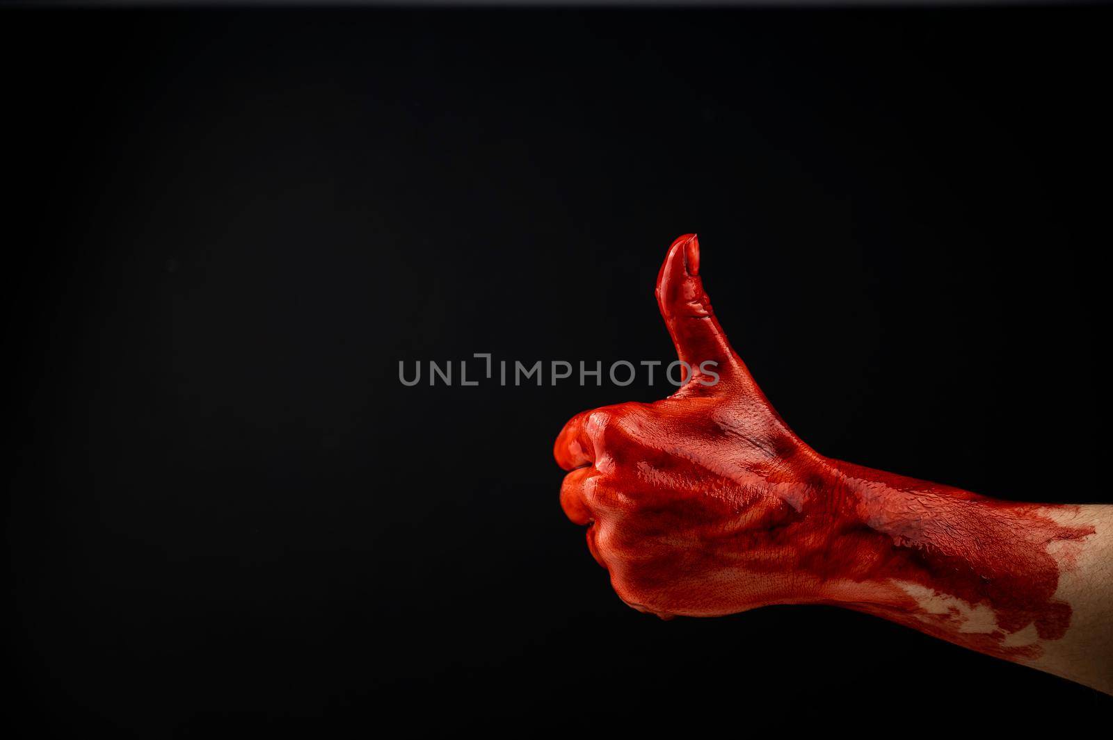 A woman's hand stained with blood shows a thumbs up on a black background. by mrwed54