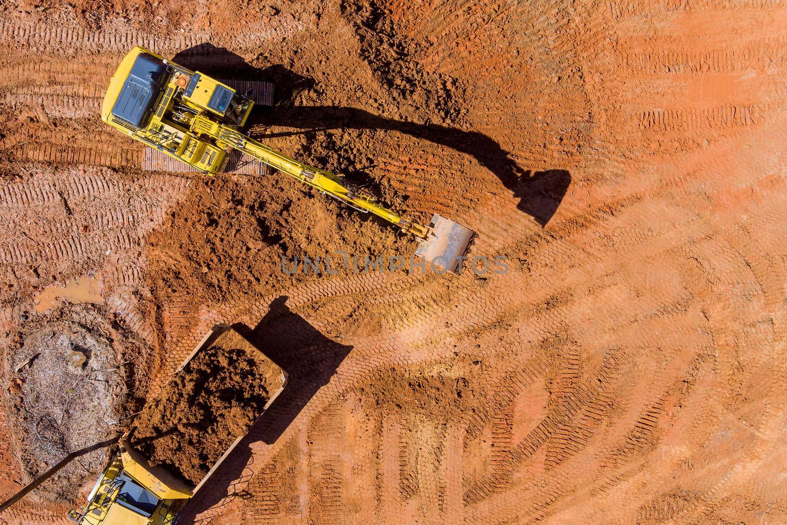 Aerial top down view of an excavator loading earth into a dump truck by ungvar