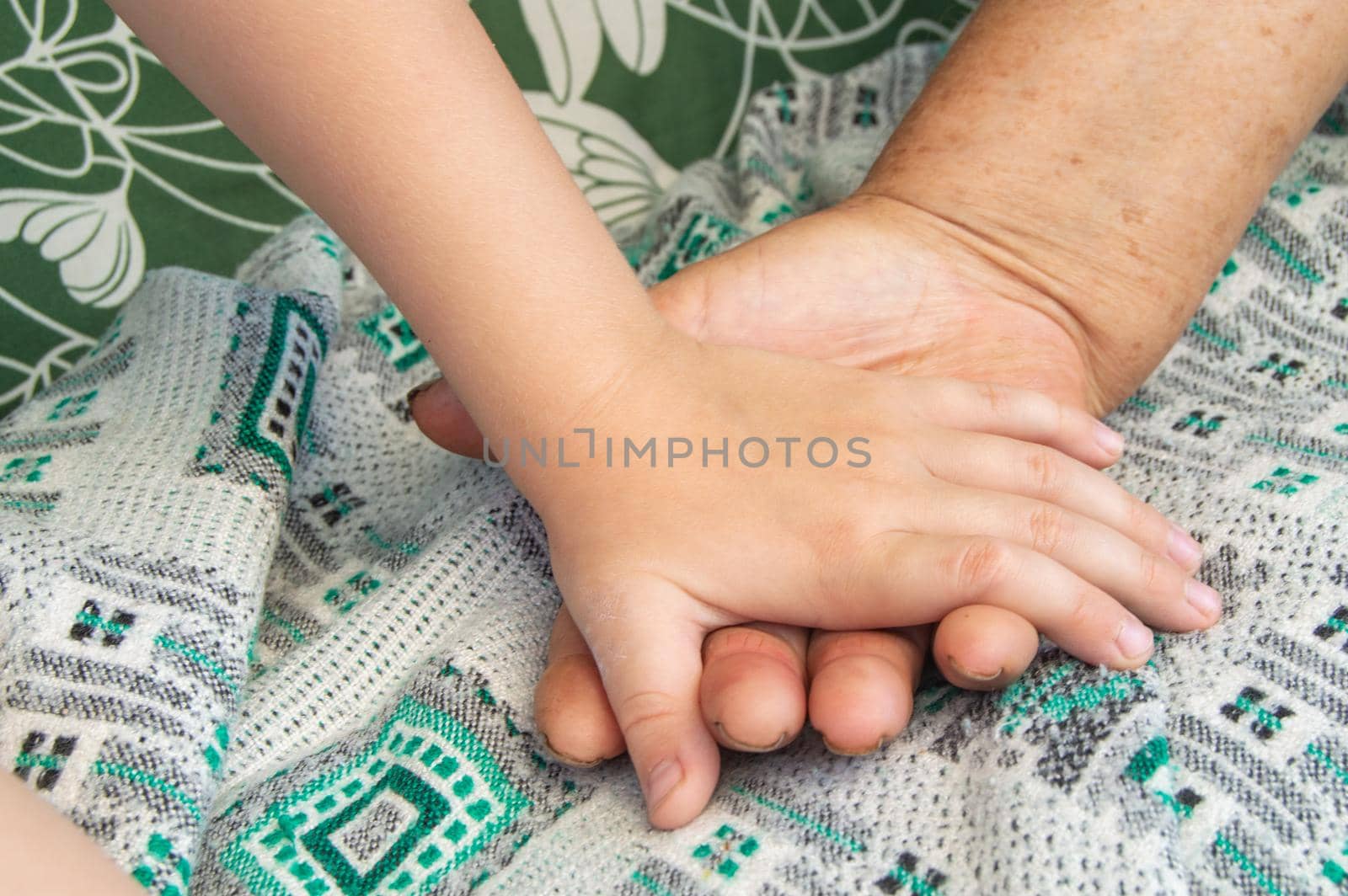 Close-up of the hands of an elderly woman and a small child. Soft focus image.