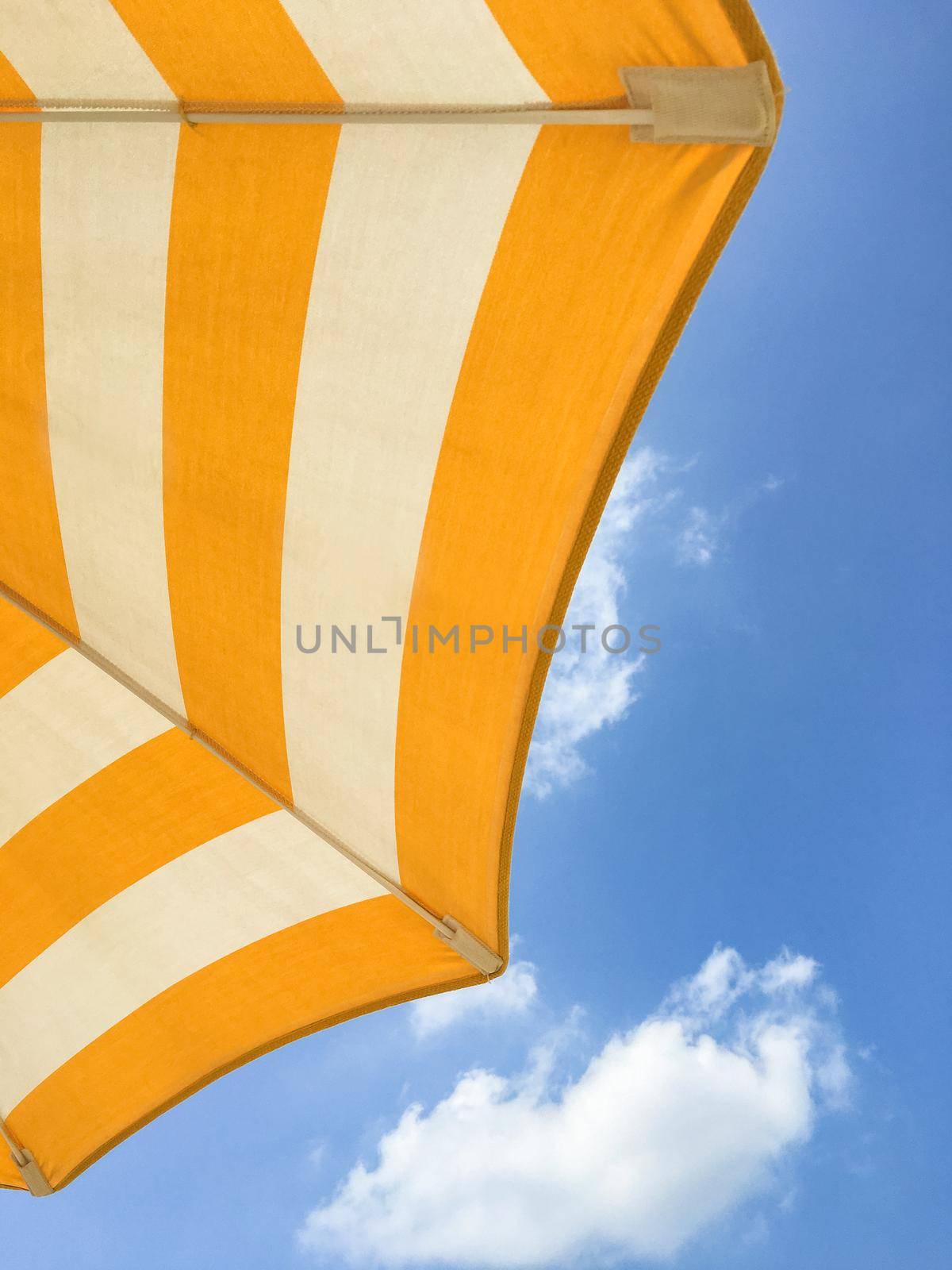 Yellow beach umbrella on a sunny day. Bright colored umbrella on the beach.