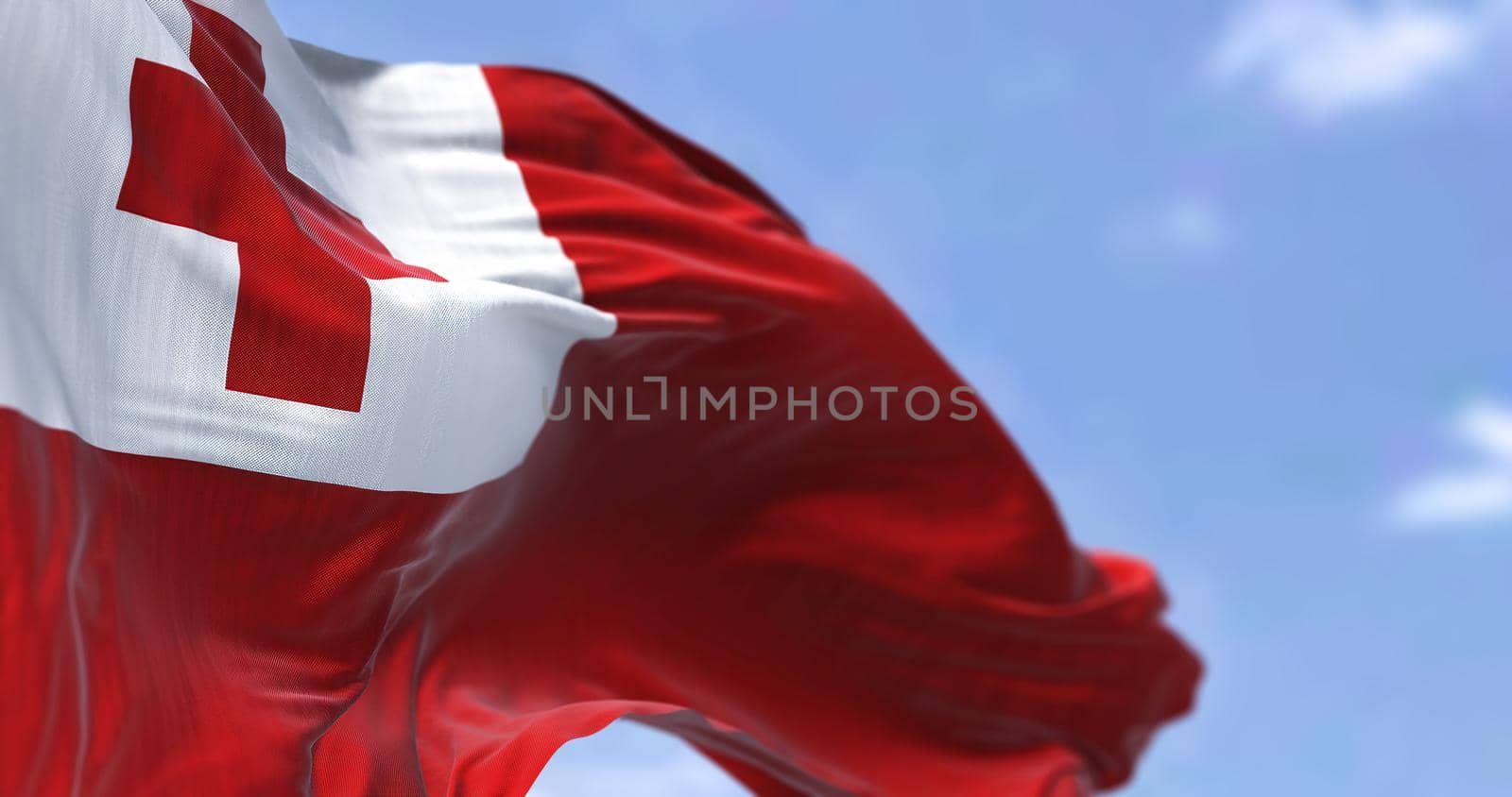 Detail of the national flag of Tonga waving in the wind on a clear day. Tonga is a Polynesian country and also an archipelago. Selective focus.