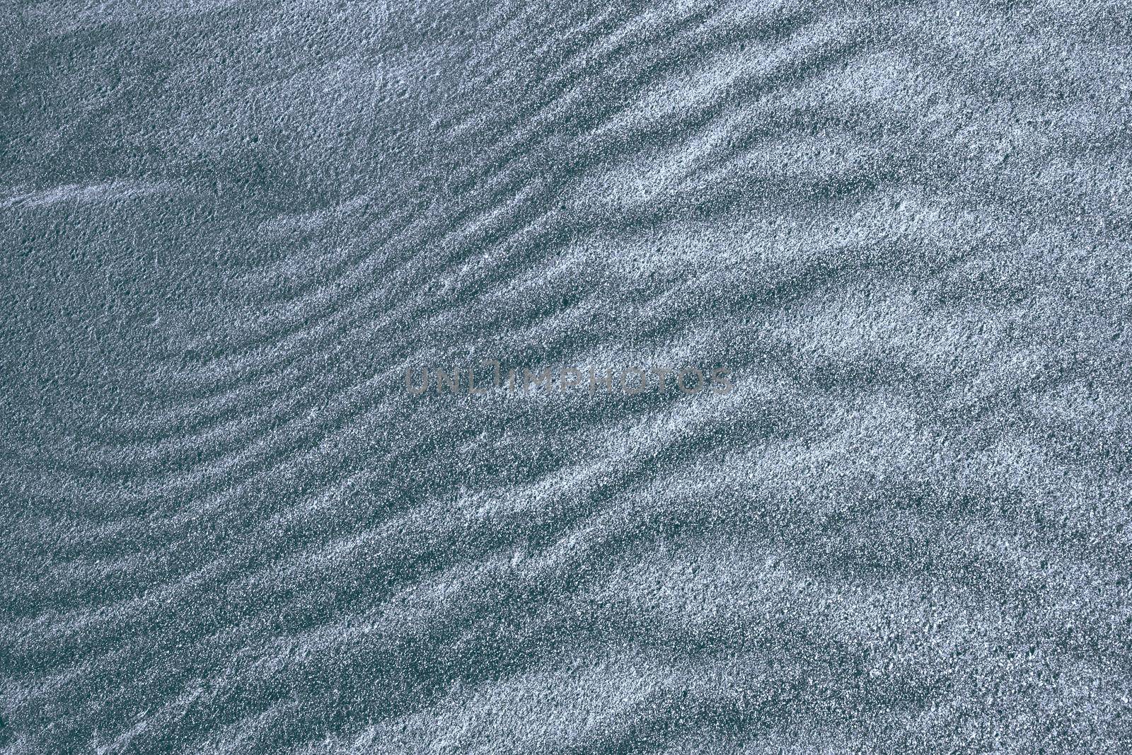Background, texture, wave pattern of oceanic sand on the beach, dark