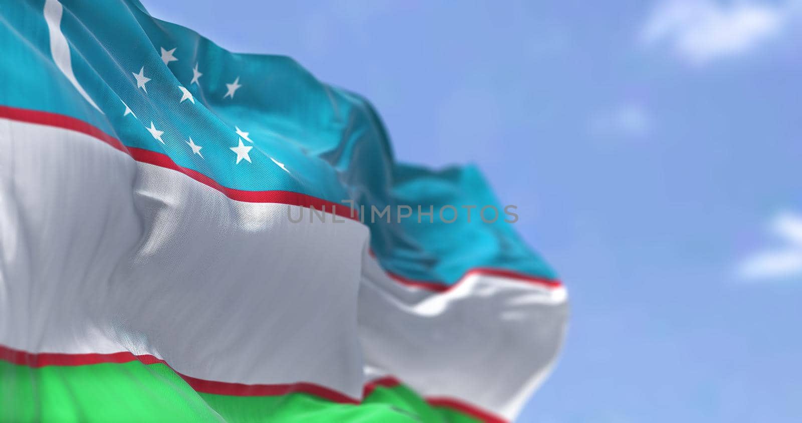 Detail of the national flag of Uzbekistan waving in the wind on a clear day. Uzbekistan is a landlocked country in Central Asia. Selective focus.