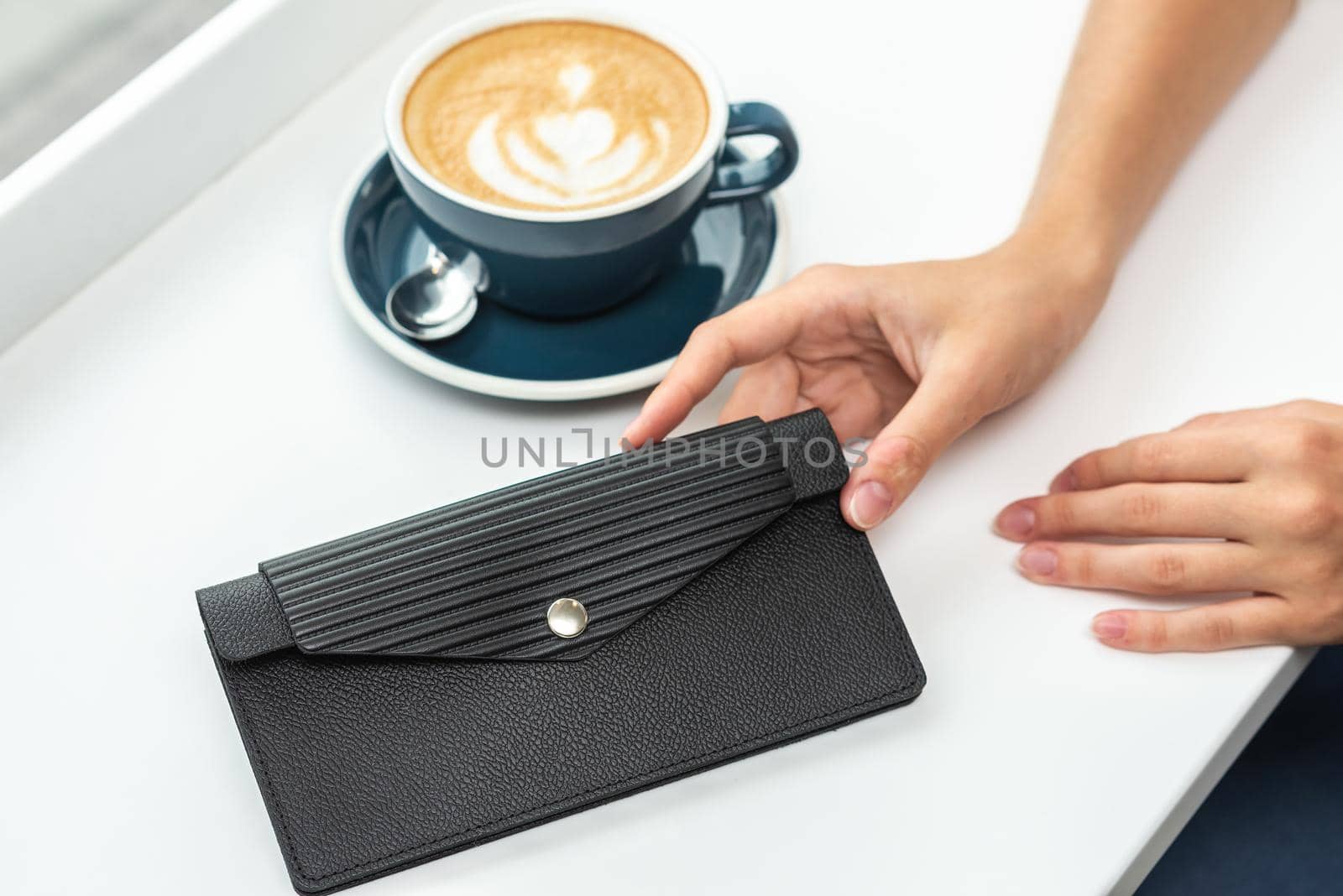 Wallet on a white table with a cup of coffee