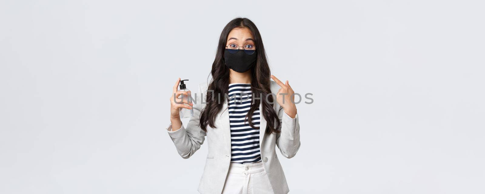 Business, finance and employment, covid-19 preventing virus and social distancing concept. Cute asian office lady explain importance of wearing face masks and use hand sanitizers during pandemic.