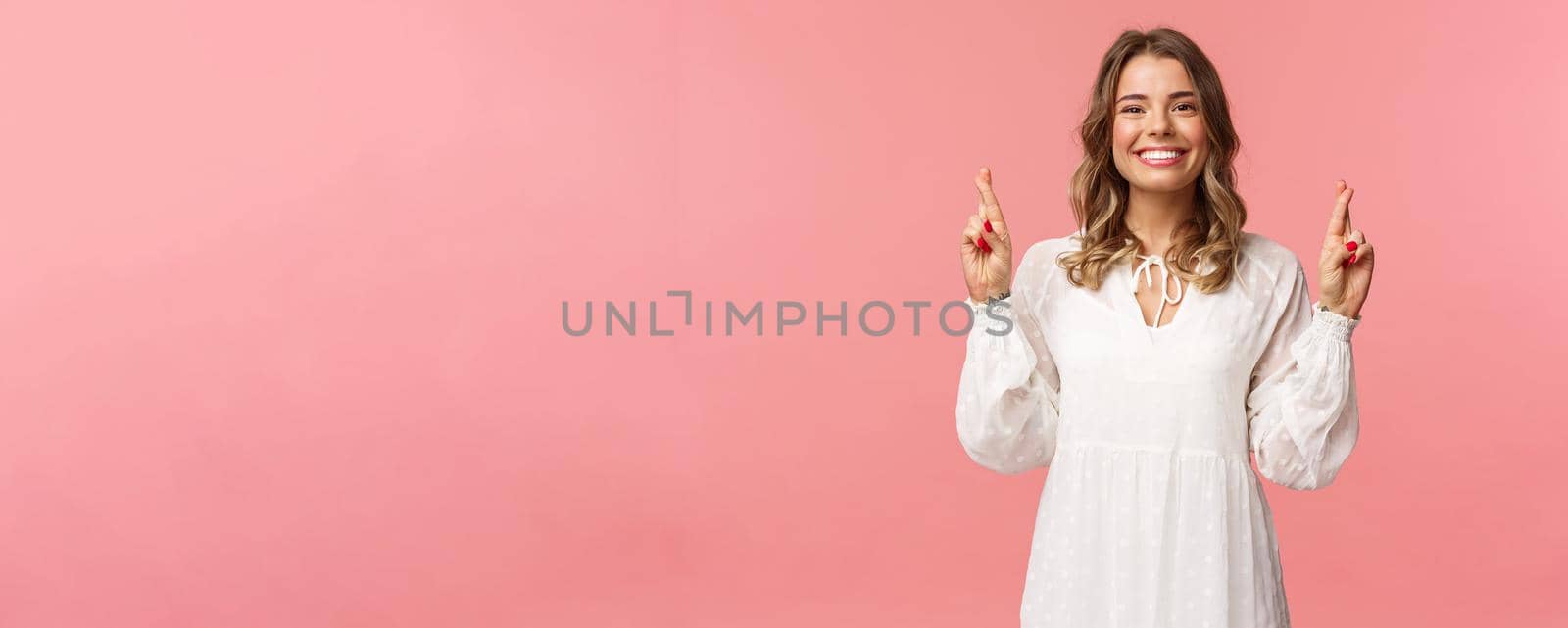 Portrait of optimistic hopeful young blond cute girl, making wish and know it come true, cross fingers good luck, smiling looking camera assertive, praying for dream fulfill, pink background by Benzoix