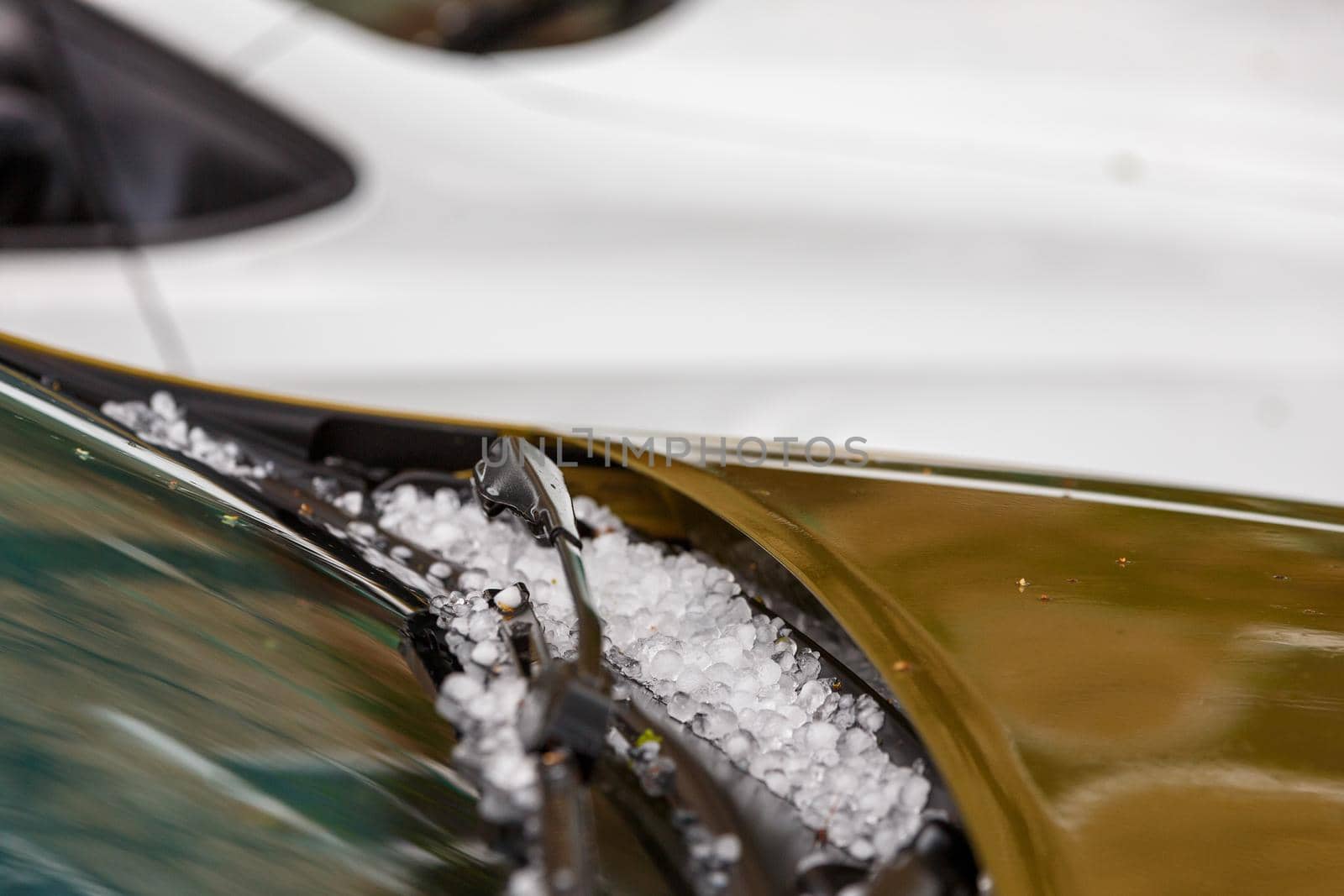 small hail ice balls on brown car hood after heavy summer storm close-up with selective focus at daylight.