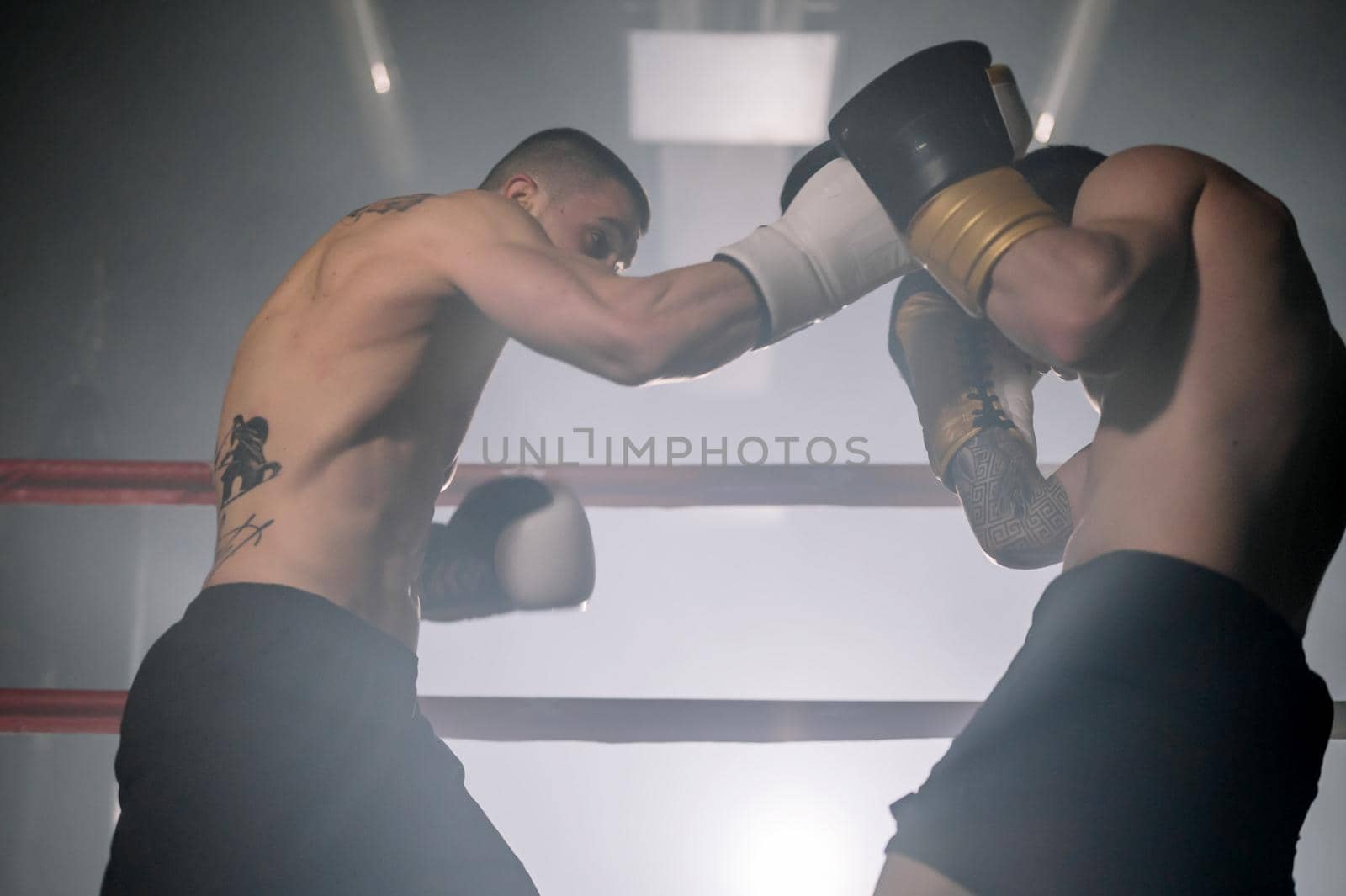 Two professional young muscular shirtless male boxers fighting in a boxing ring. by HERRAEZ
