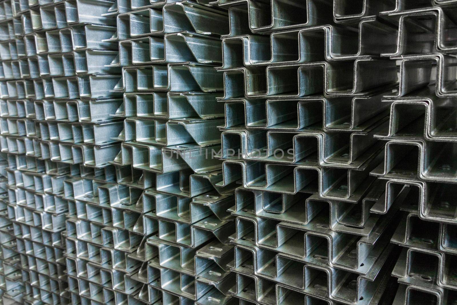 Full frame stack of bended zinc plated sheet metal parts - close-up with selective focus and blur. Sheet bending parts backdrop.