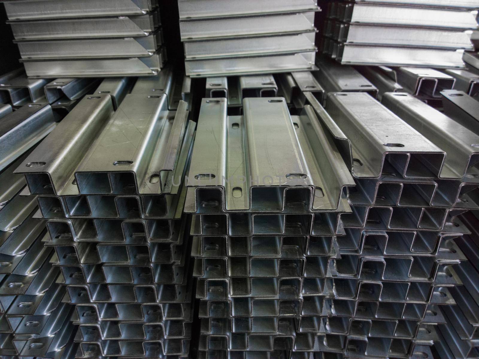 Full frame stacks of bended zinc plated sheet metal parts - close-up with selective focus and blur. Sheet bending parts backdrop.