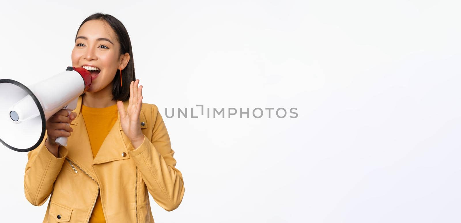 Attention announcement. Image of asian woman shouting in megaphone, recruiting, searching people, sharing information, standing over white background.