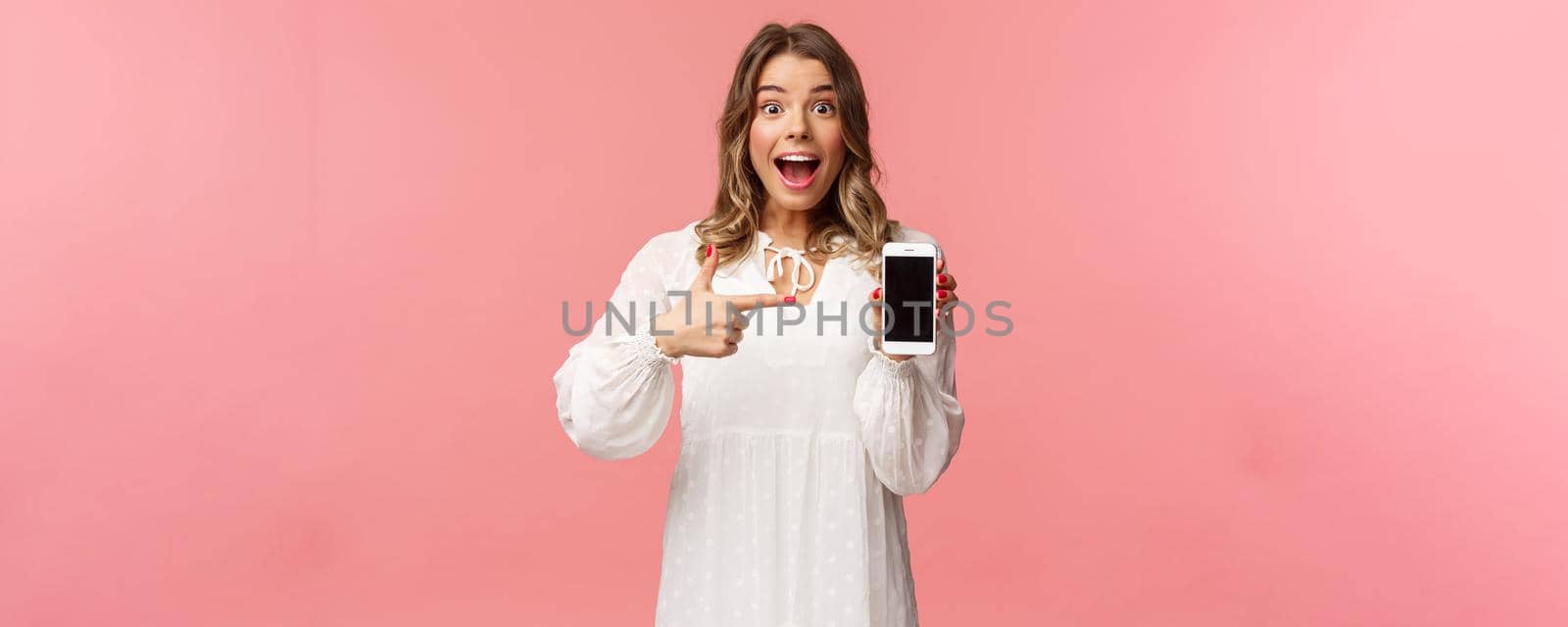 Portrait of impressed, excited young blond woman showing something awesome on display, pointing mobile phone screen and smiling astonished, brag with her recent match on dating app.