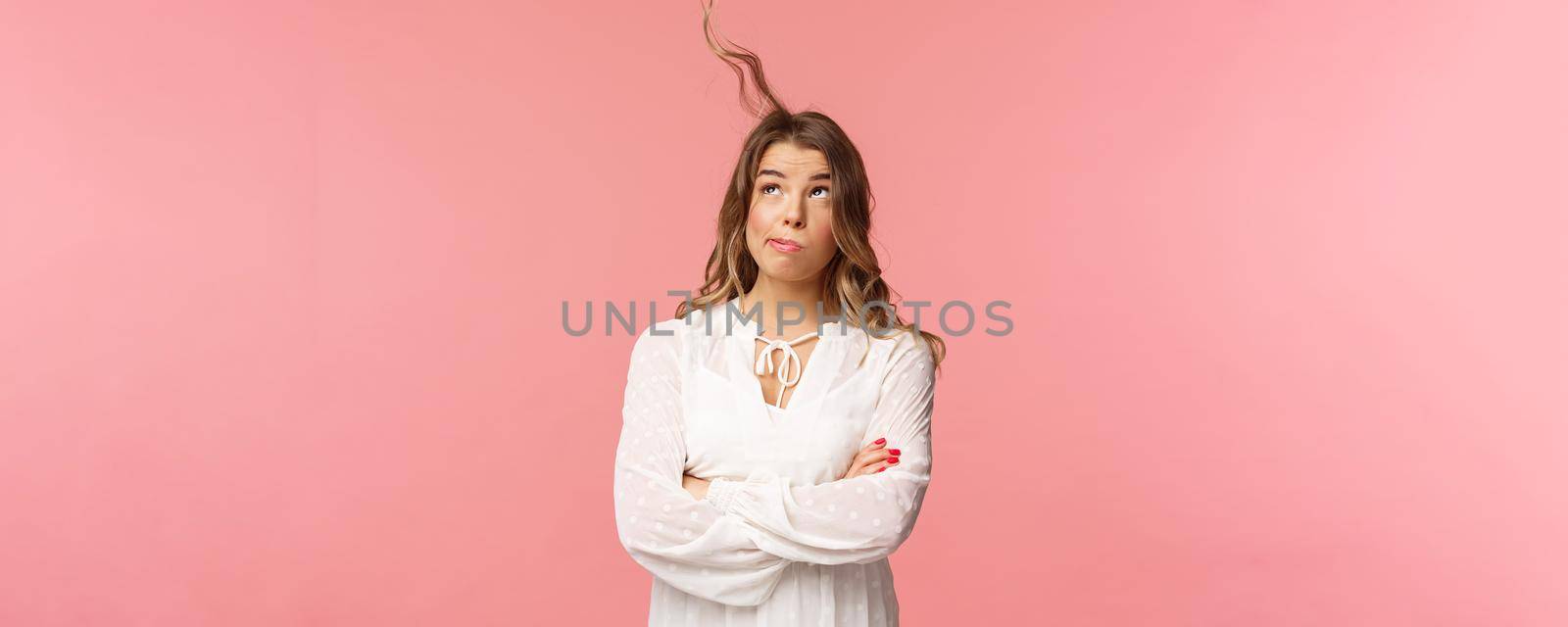 Holidays, spring and party concept. Portrait of troubled busy young blond girl over pink background, trying blew away annoying hair strand from face, blow at hair, look up, stand pink background.