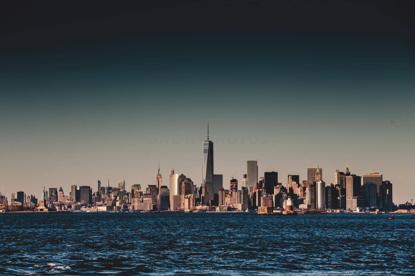 New York City Manhattan downtown skyline at dusk with skyscrapers illuminated over Hudson River panorama. Vertical composition.