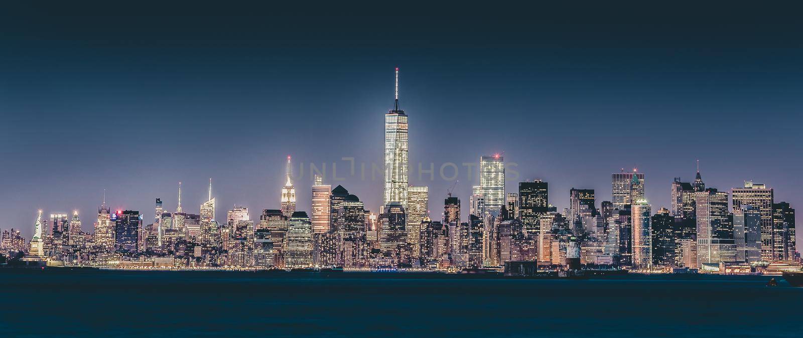 New York City Manhattan downtown skyline at dusk with skyscrapers illuminated over Hudson River panorama. Vertical composition.