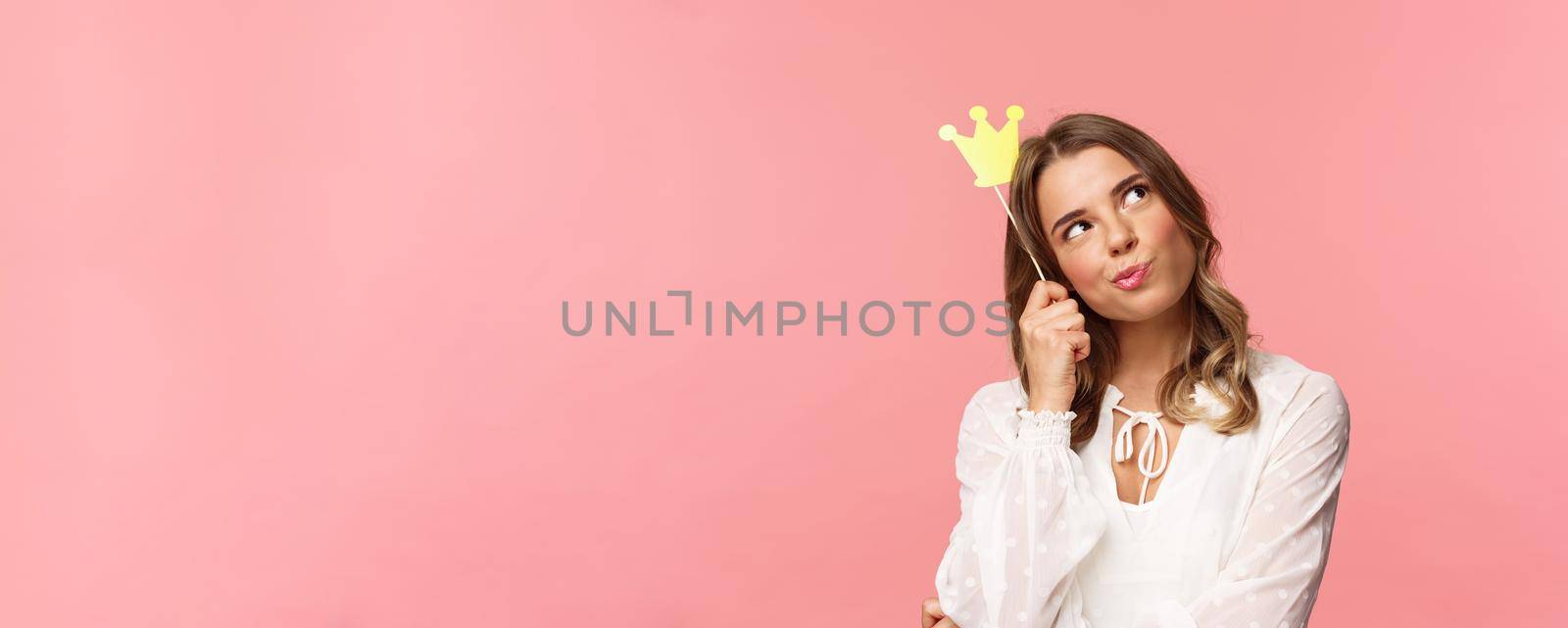Spring, happiness and celebration concept. Close-up portrait of thoughtful young confident and attractive girl feeling like queen of night party, daydreaming, thinking with crown mask on head.