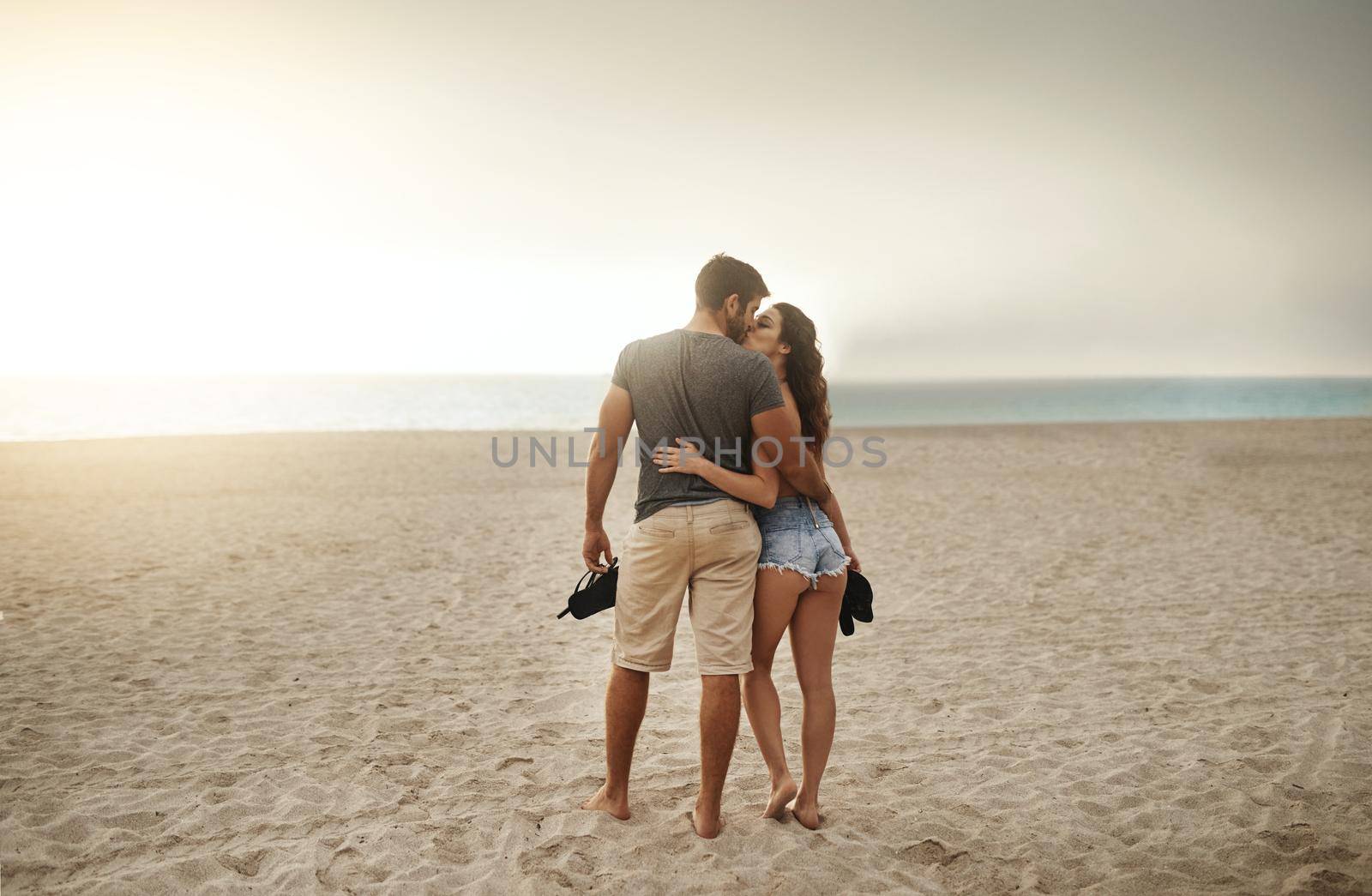 Romantic seaside strolls at sundown. Shot of a young couple spending a romantic day at the beach. by YuriArcurs