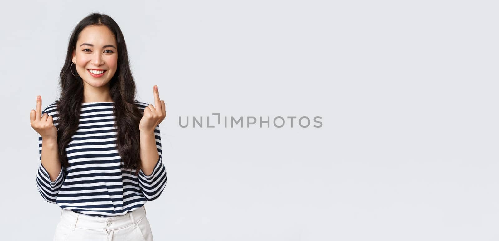 Lifestyle, beauty and fashion, people emotions concept. Unbothered and careless young happy smiling woman dont give a damn, showing middle fingers and feeling good, white background.