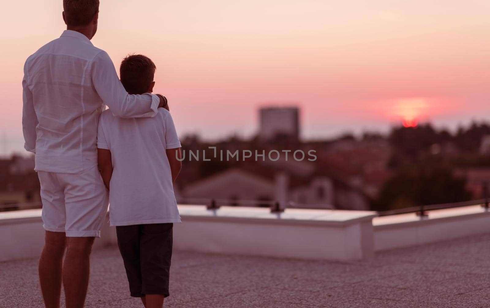 Father and son spend time together on the roof of the house while enjoying the sunset. Selective focus by dotshock