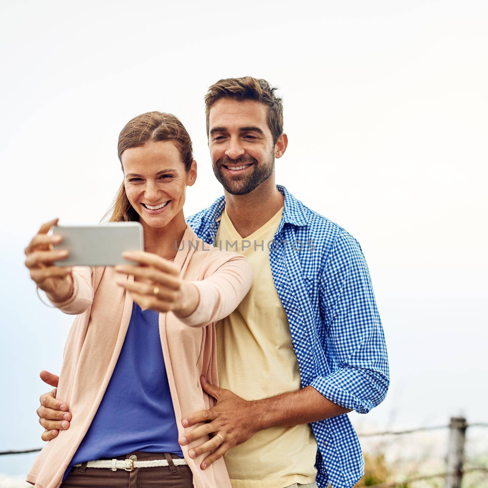 Taking a selfie on a beautiful day. Cropped shot of an affectionate couple taking selfies outside. by YuriArcurs