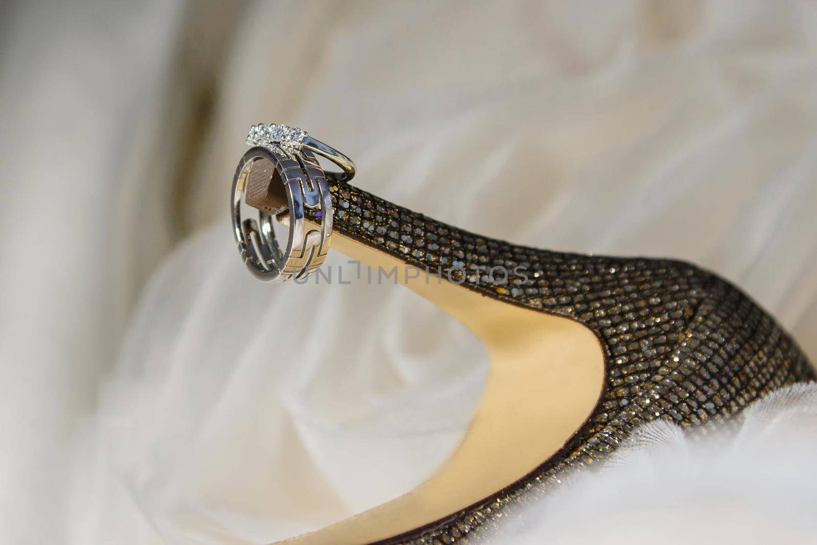 close up of wedding rings on bride's shoes by ungvar