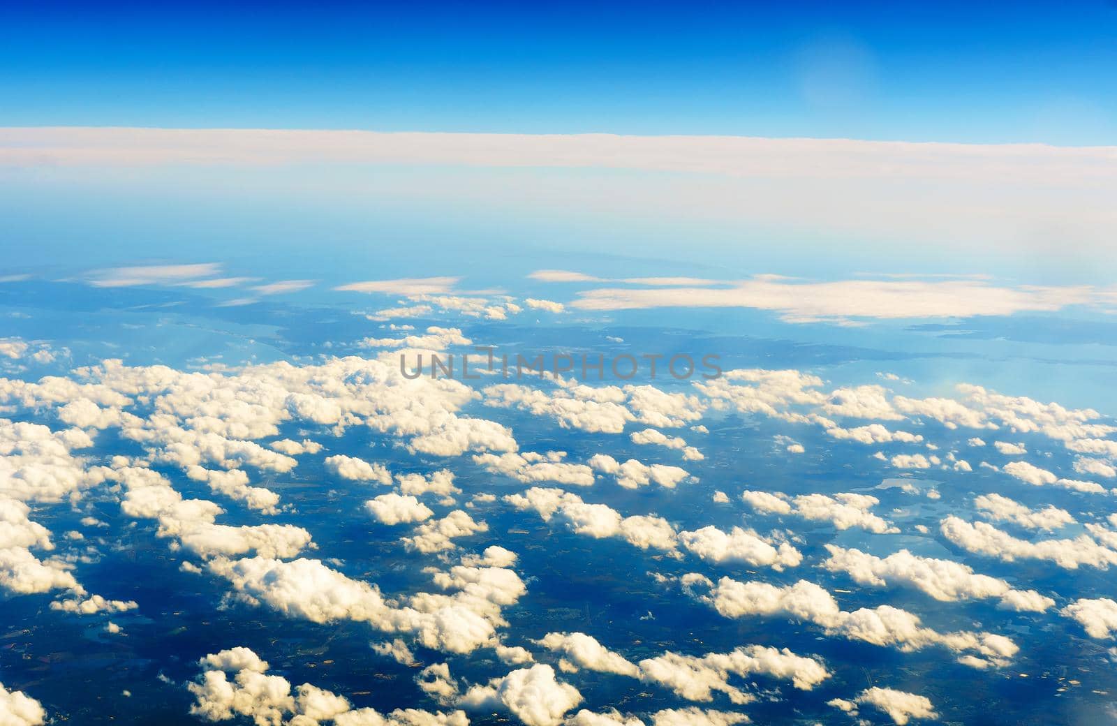 Fluffy white clouds and blue sky seen from airplane. by ungvar