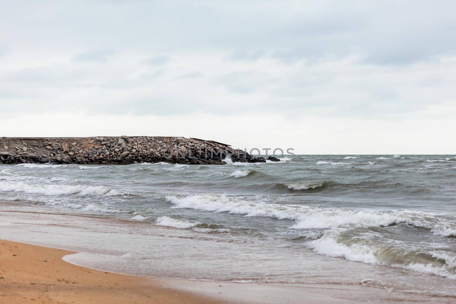 Huge waves raging in the sea and seagulls in the spray of waves. Storm at sea. Birds fly over the waves. Nature, environment, rough weather, danger