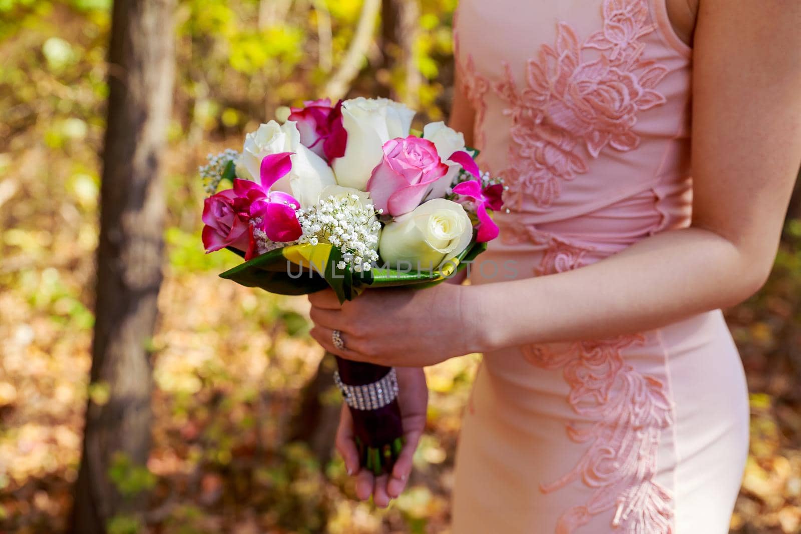 young caucasian woman in pink lace dress holds a bouquet with flowers and pink garden roses in her hands