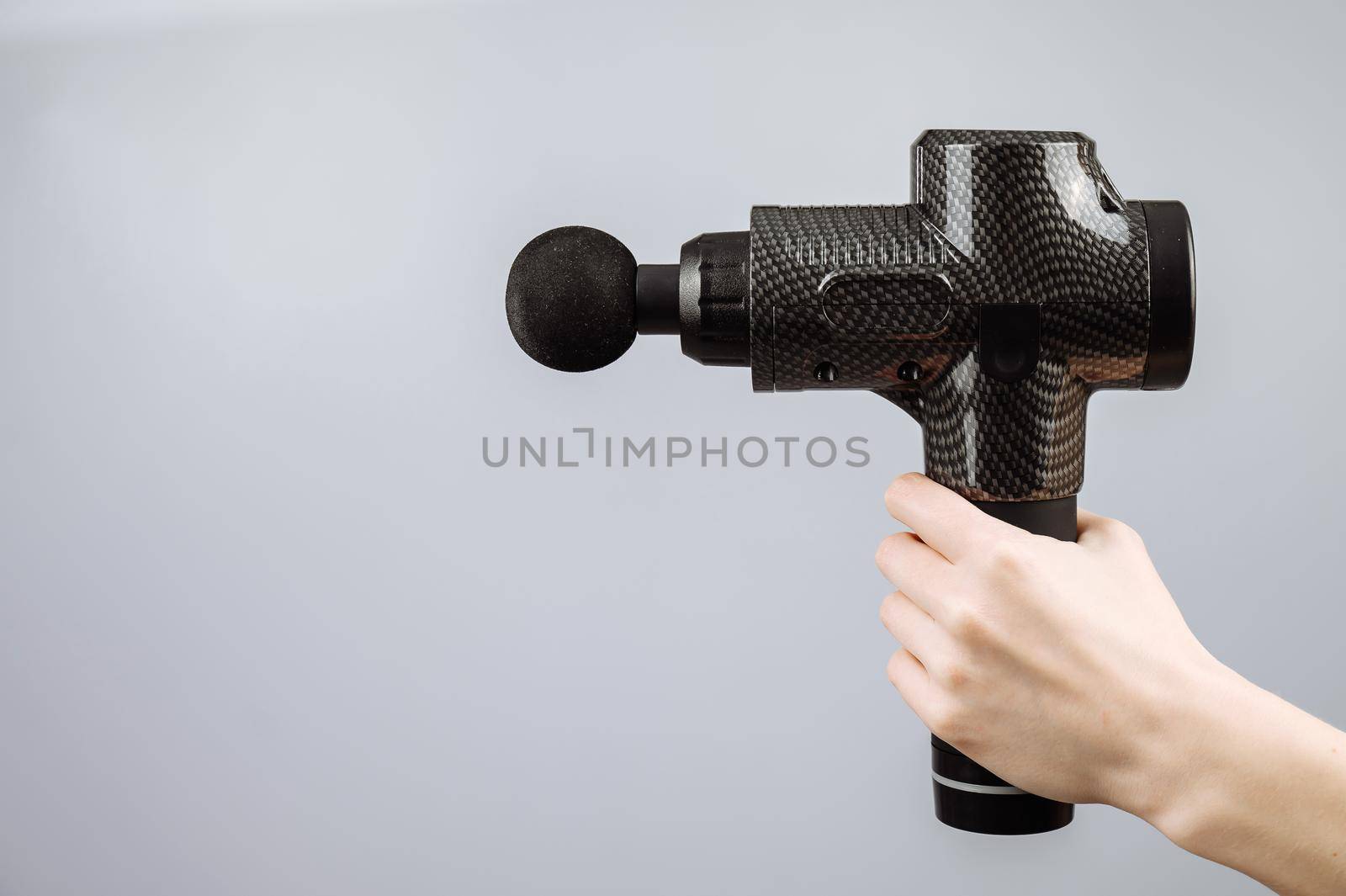 Close-up of a female hand with a portable massager gun on a white background. by mrwed54