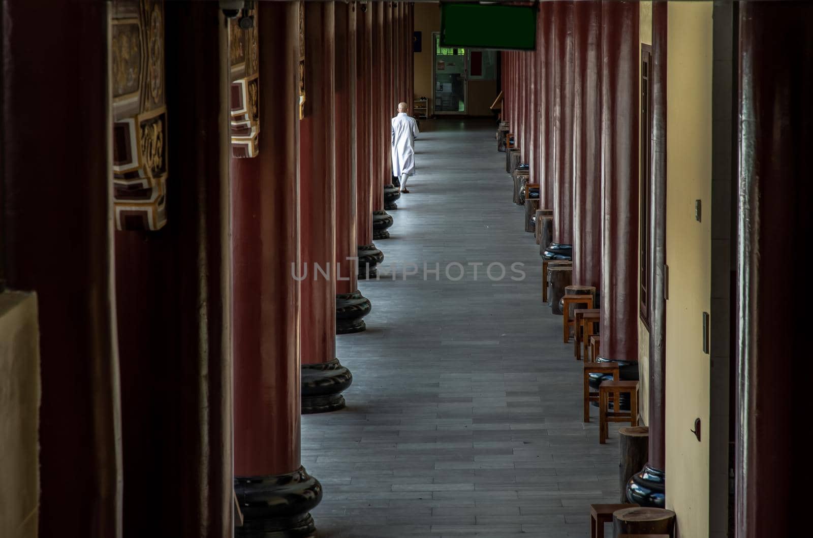 Bangkok, Thailand - Feb 19, 2022 : Back side of Chinese buddhist monk white robe walking on pathway in Fo Guang San Temple. Vertical abstract, Selective focus.