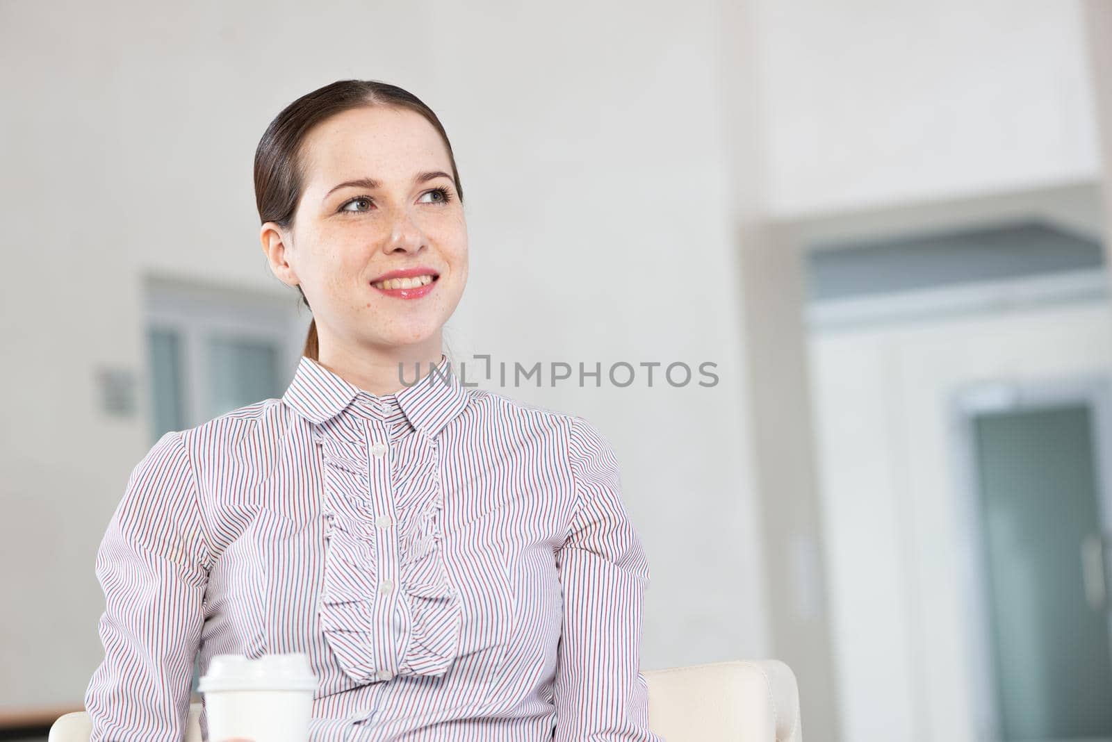 Portrait of a young attractive woman in a light chair, in an office space
