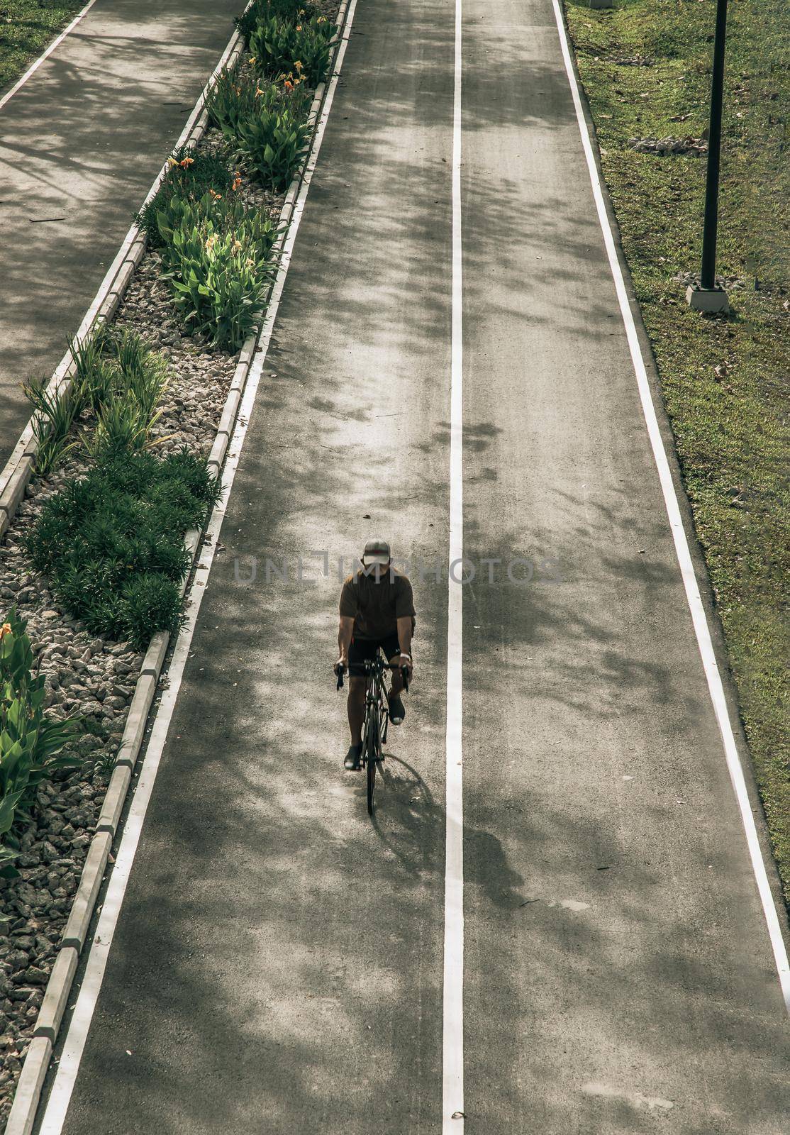 The cyclist riding a mountain bike an road along in a city park.  by tosirikul