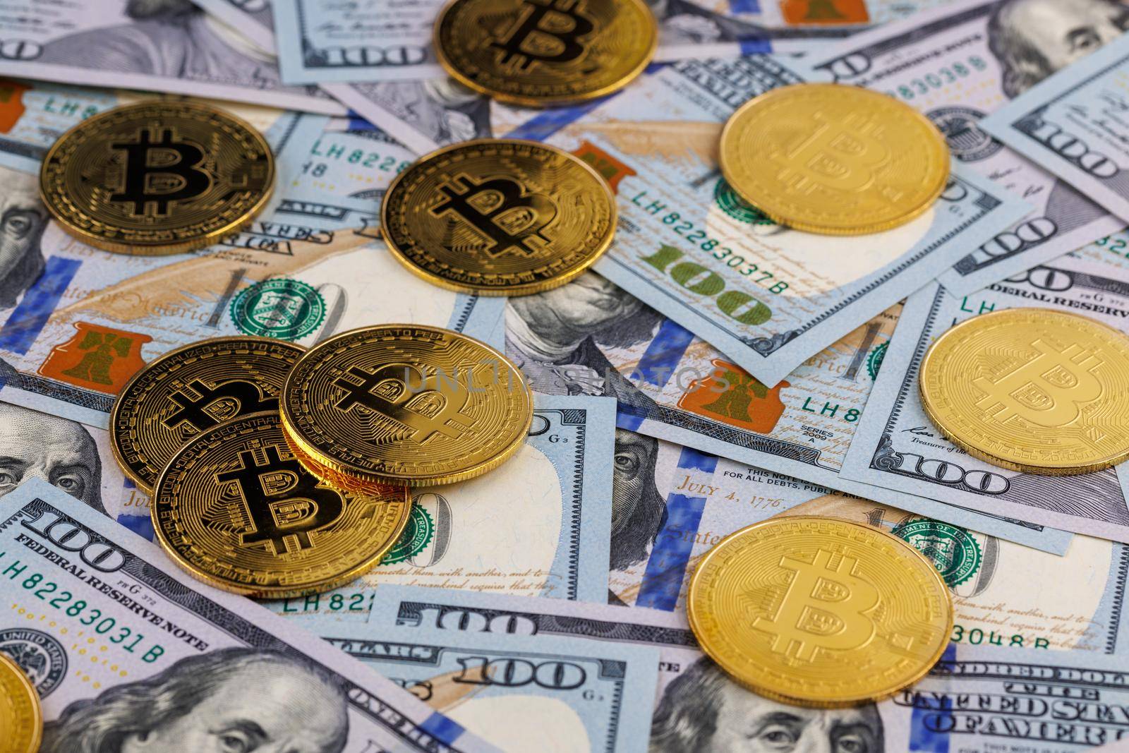yellow bitcoin coins scattered over US dollar paper banknotes, cryptocurrency and fiat money exchange concept, closeup with selective focus