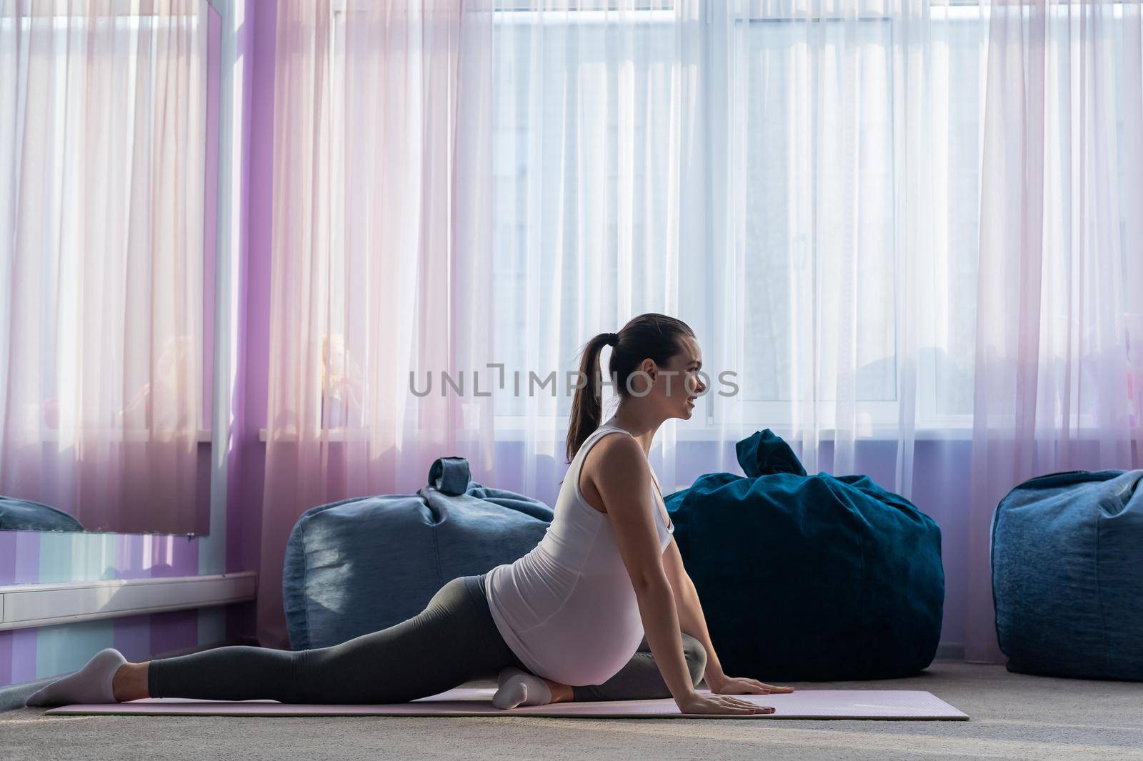 Beautiful young pregnant woman is engaged in pilates. The expectant mother plays sports while waiting for the birth of a child